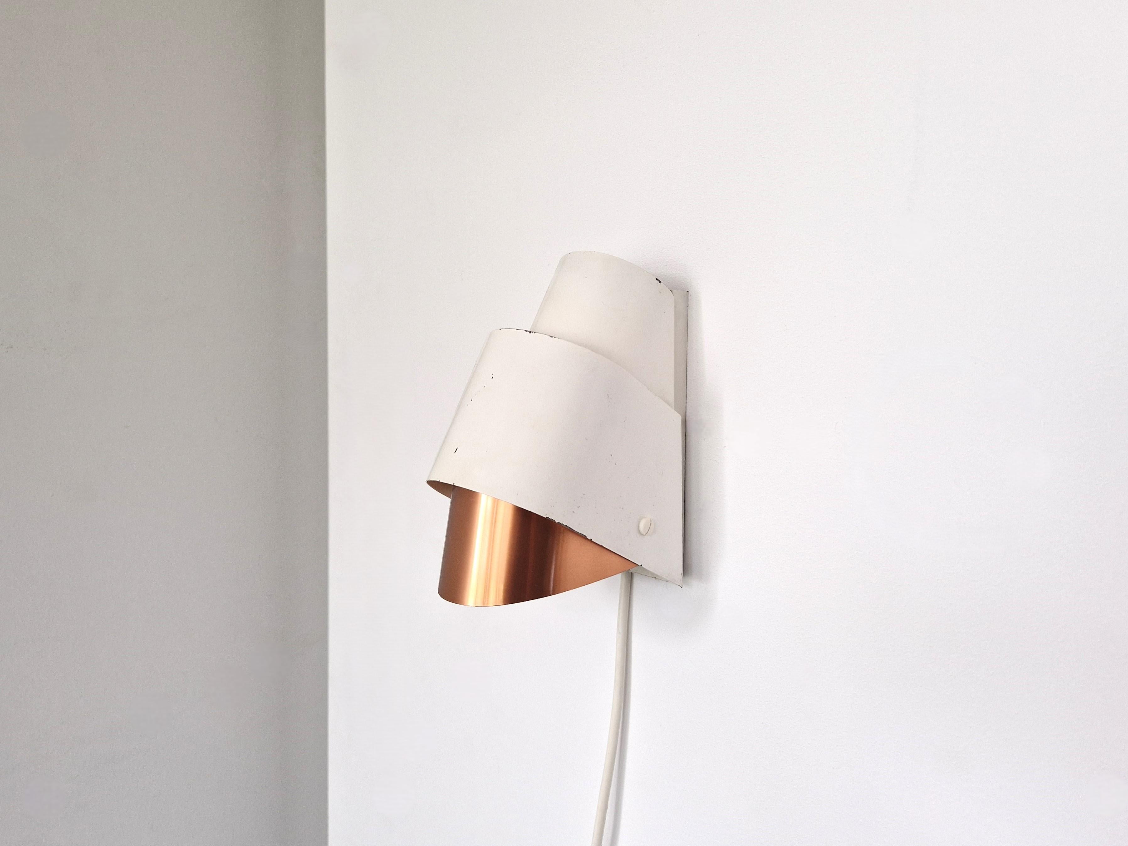 Cette lampe murale moderniste et rare, modèle V-317, a été conçue par Hans-Agne Jakobsson pour Markaryd en Suède dans les années 1960. Il se compose de 2 feuilles courbes en métal peint en blanc (finition originale) et d'une feuille de cuivre brossé