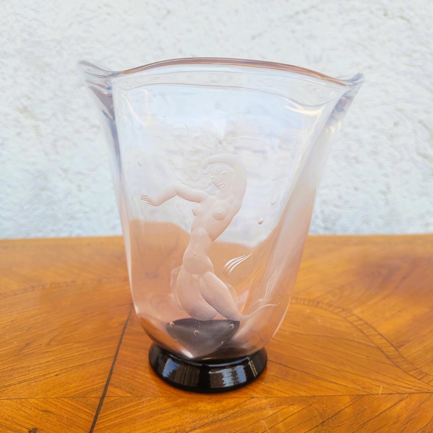 Clear glass vase engraved with a mermaid motif; the shape of the vase is reminiscent of sea waves  

Vase on a black glass base, signed Orrefors and Vicke Lindstrand and numbered 1220.01.1(?)  

Orrefors is a Swedish glassworks founded in 1898,