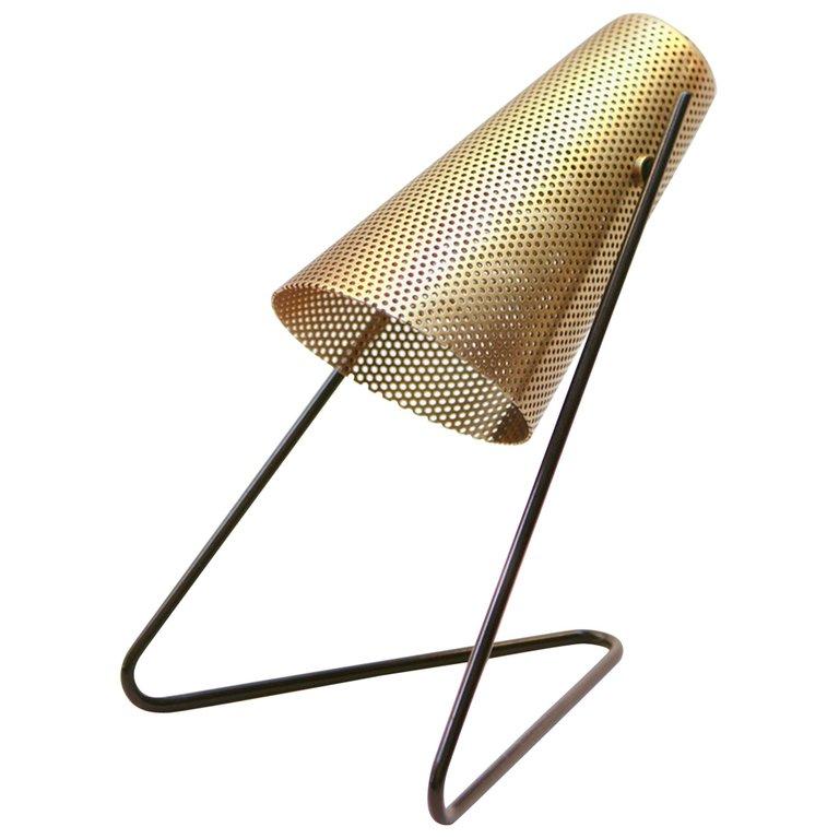 Designed in collaboration with Commune design, the V-Lite doubles as a table lamp and a wall sconce. As a sconce, the fixture comes with a large brass ball hook for wall mounting. The perforated brass shade tilts up and down. Finish options for the