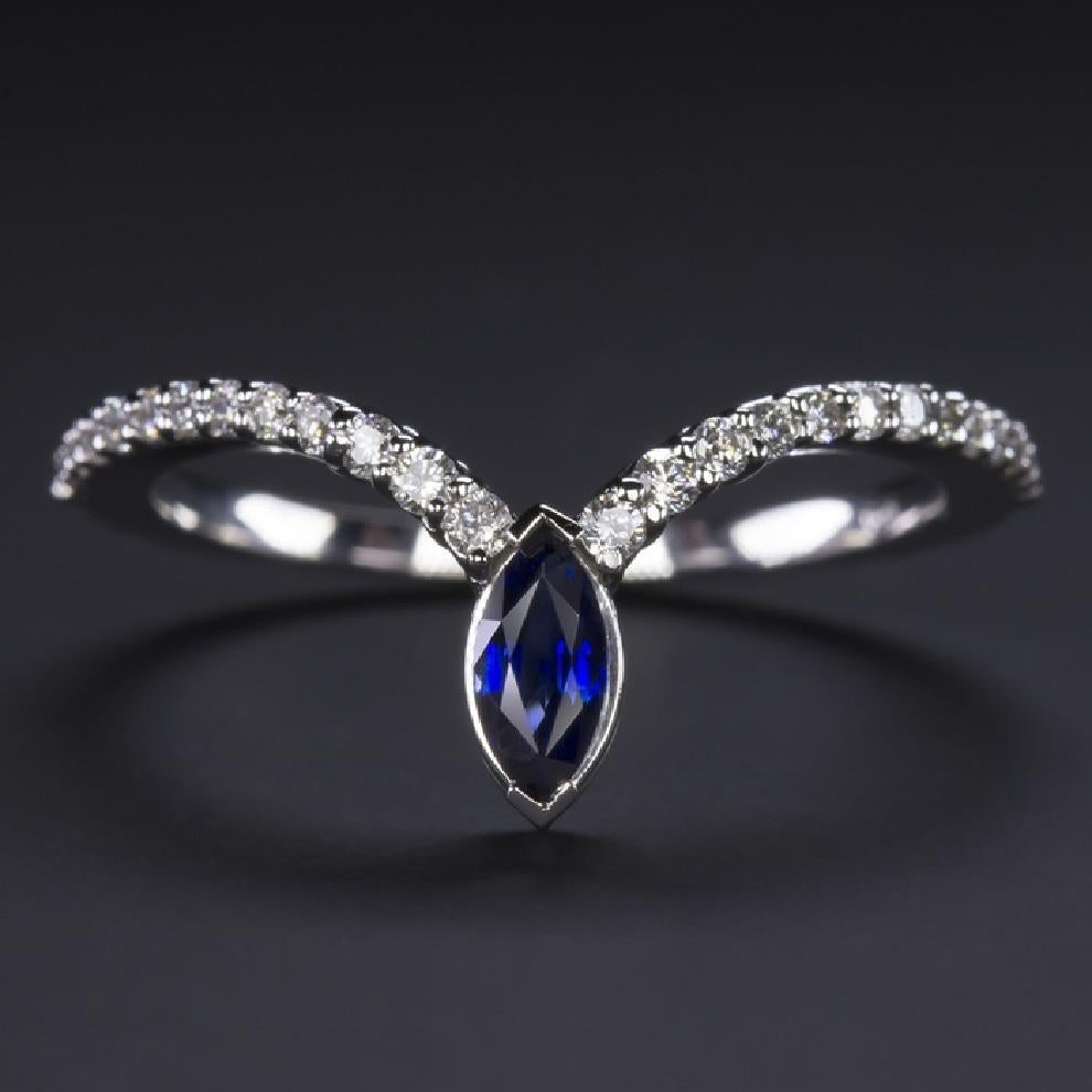 Stunning natural diamond and sapphire ring with a beautiful modern design. The setting, a sparkling pavé of brilliantly set white diamonds, curves very gracefully to the tip of the ring, which is decorated with a stunning royal blue sapphire. This