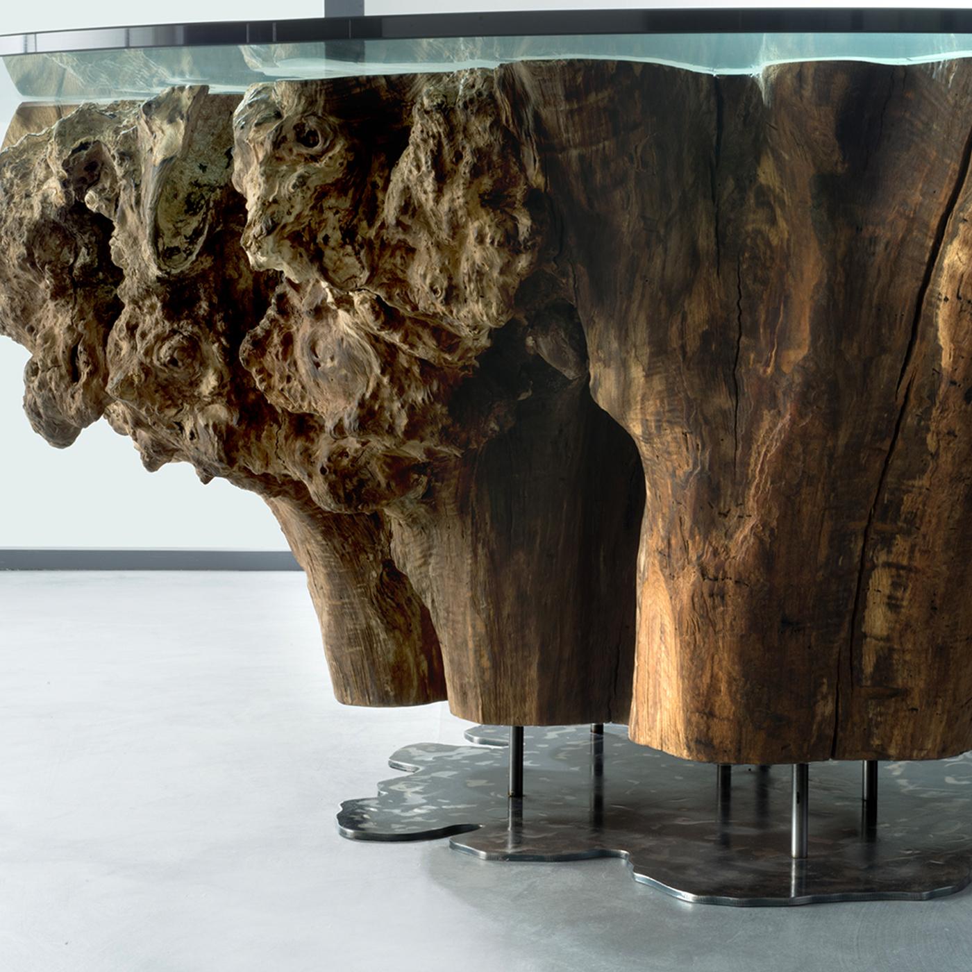 This handmade table boasts a majestic and unique character: the root of a century-old tree is extracted from the ground, smoothed and fixed on a support, creating a prestigious, singular sculptural piece of functional decor. Enhancing the root's
