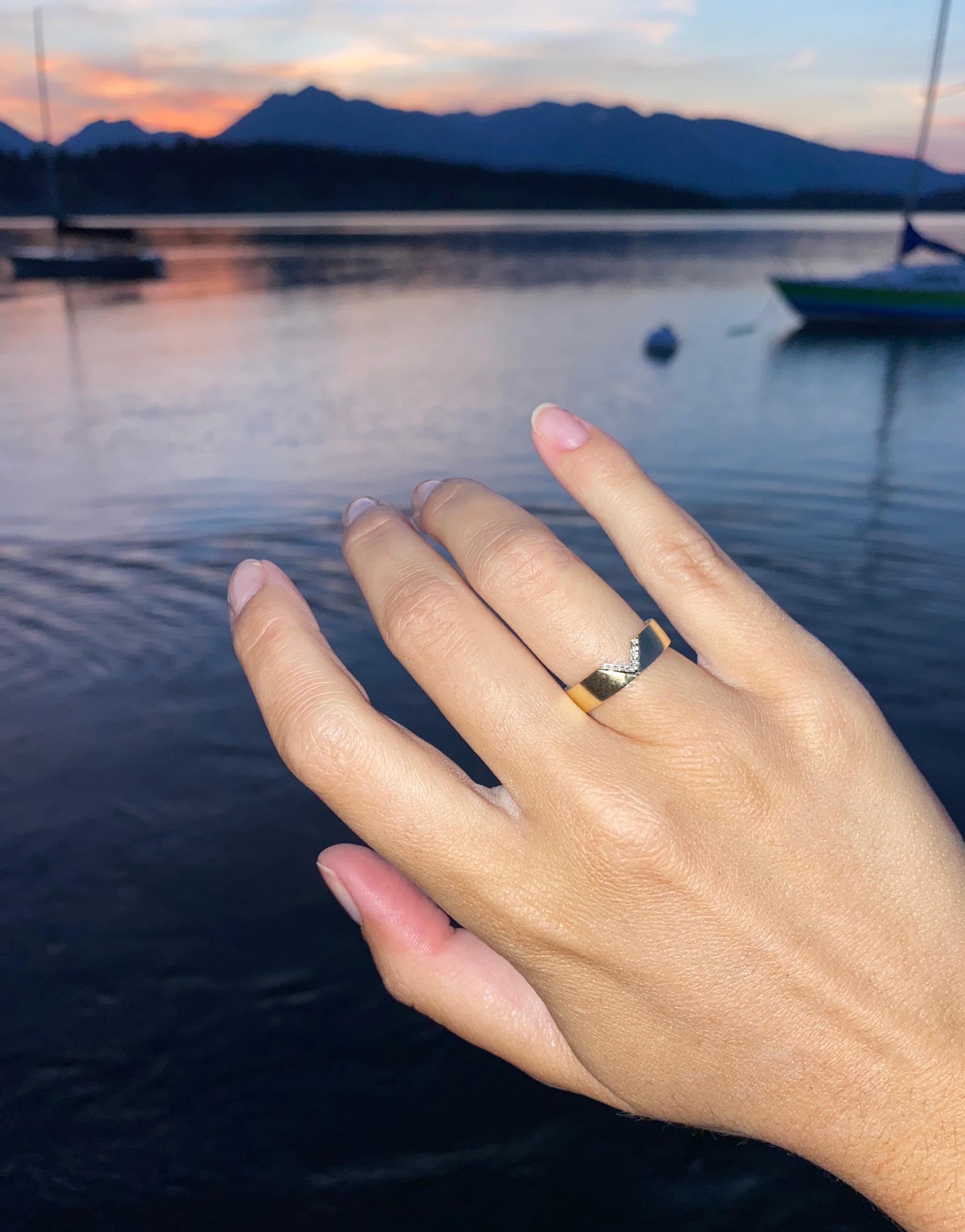 Un gran anillo de oro amarillo de 14 quilates con un corte en forma de V recubierto de micropavé de diamantes redondos que suman 0,05 quilates. El anillo mide 5 mm de ancho. Una pieza moderna y minimalista que queda genial sola o combinada con otras