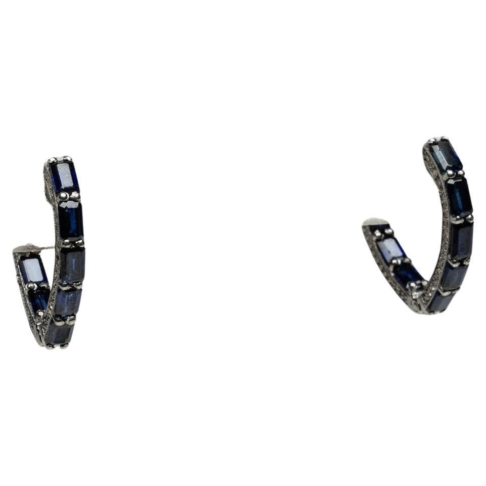 Uno splendido paio di cerchi a forma di V con zaffiri blu.  Gli zaffiri hanno un taglio a smeraldo con un design a rovescio, in modo che le pietre sulla parte anteriore e posteriore dei cerchi siano rivolte in avanti.  Ci sono diamanti rotondi a