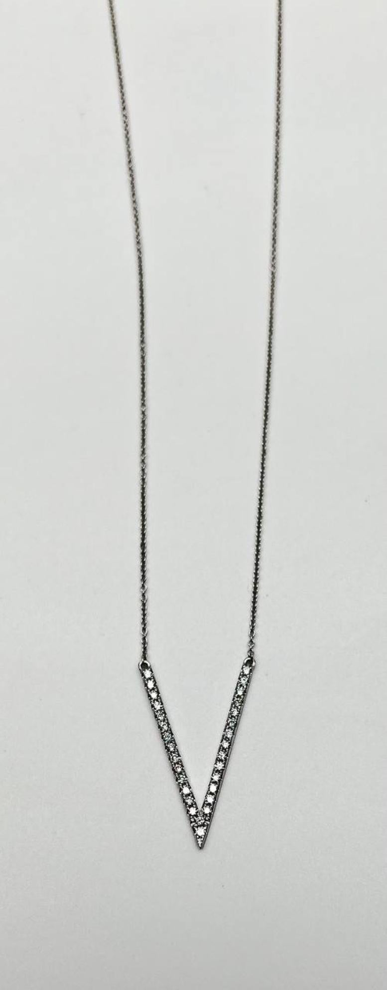 The necklace features a sleek V-shaped pendant adorned with small, sparkling diamonds. The pendant is suspended from a delicate chain. Ideal for adding a touch of elegance to any outfit. 14K White Gold. 0.40 CTW G/VS Quality