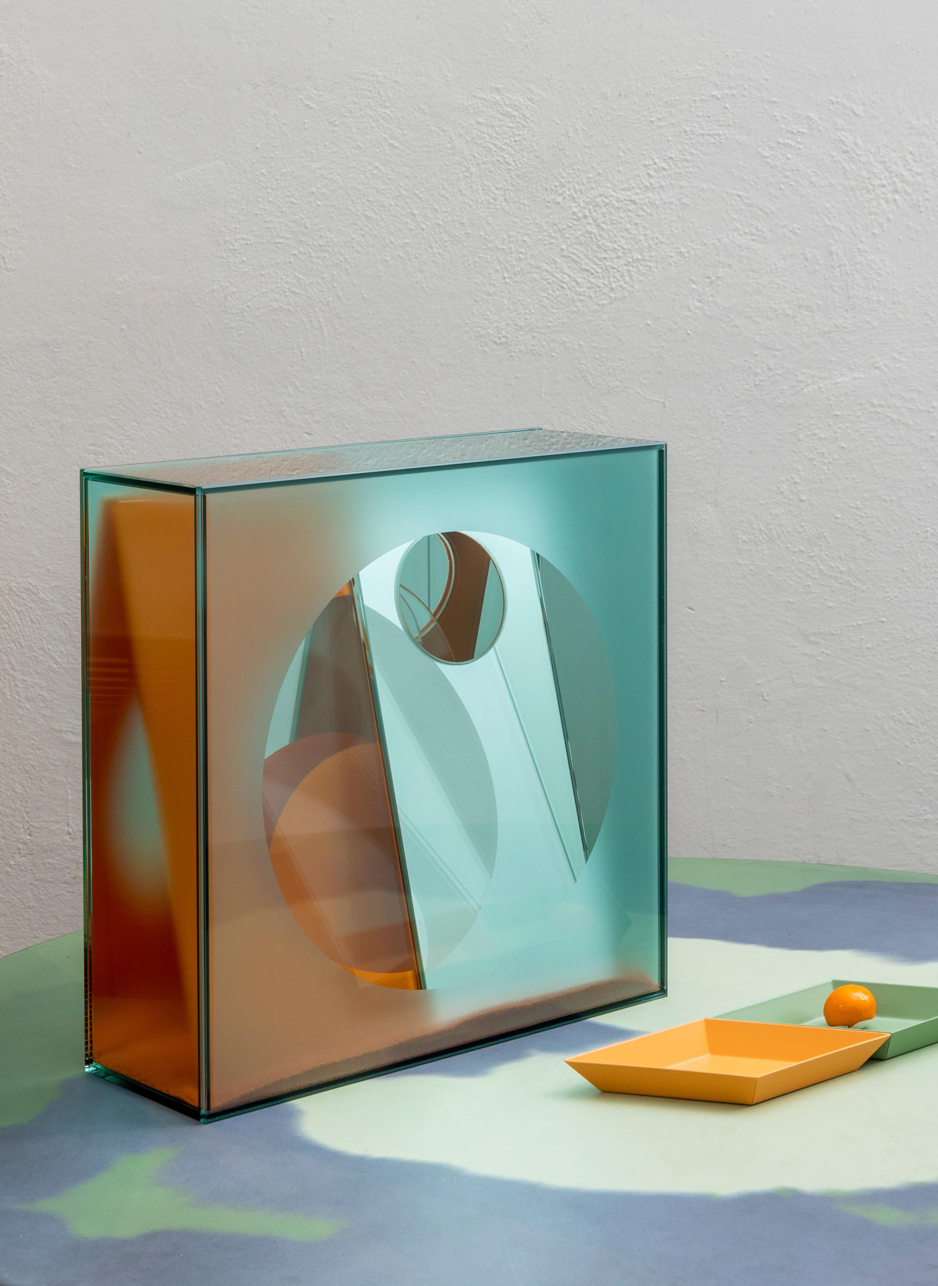 Una ilustración tridimensional que adquiere volumen y forma a través de zonas en luz y otras en sombra. La deconstrucción de los reflejos en varios niveles se define gracias a la alternancia calibrada de zonas transparentes, reflectantes, satinadas