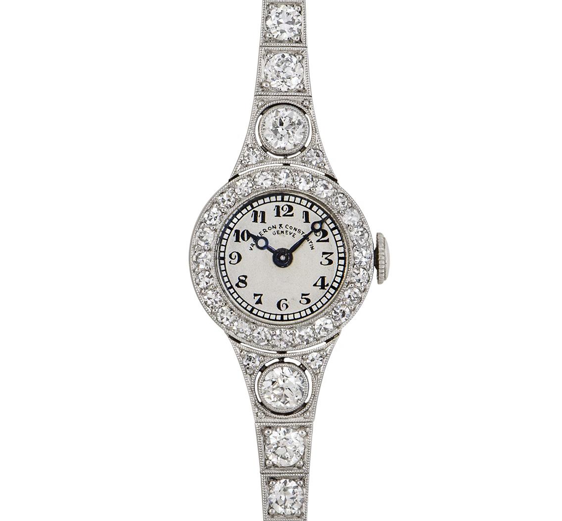 A 15 mm Platinum Vintage Ladies Cocktail Dress Wristwatch from the 1920s, silver dial with arabic numerals, blued steel hands, a fixed platinum bezel set with 24 round brilliant cut diamonds (~0.33ct), platinum shoulders each set with 3 round
