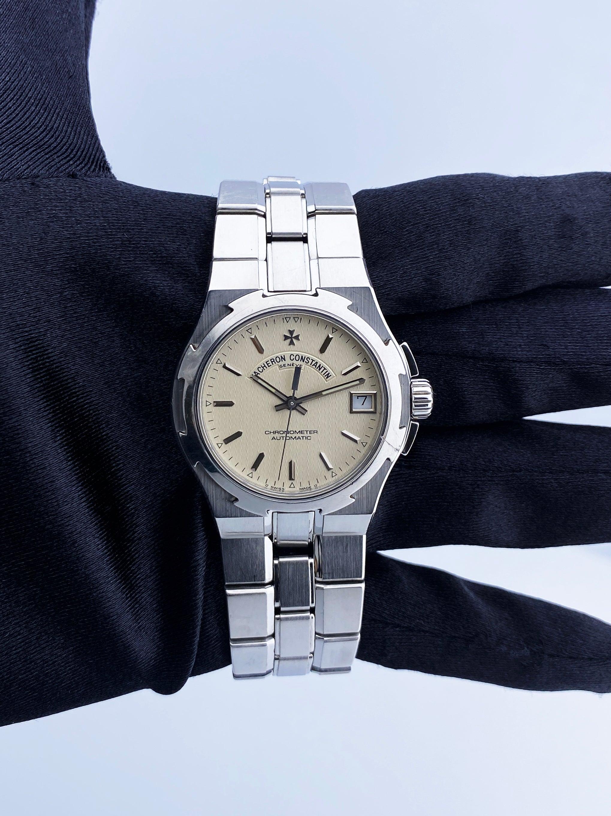 Vacheron Constantin Overseas 42050 Watch. 36mm stainless steel case  with stainless steel bezel. Off-White texture dial with steel gold luminous hands and index hour markers. Minute makers on the outer dial. Date display at 3 o'clock position.
