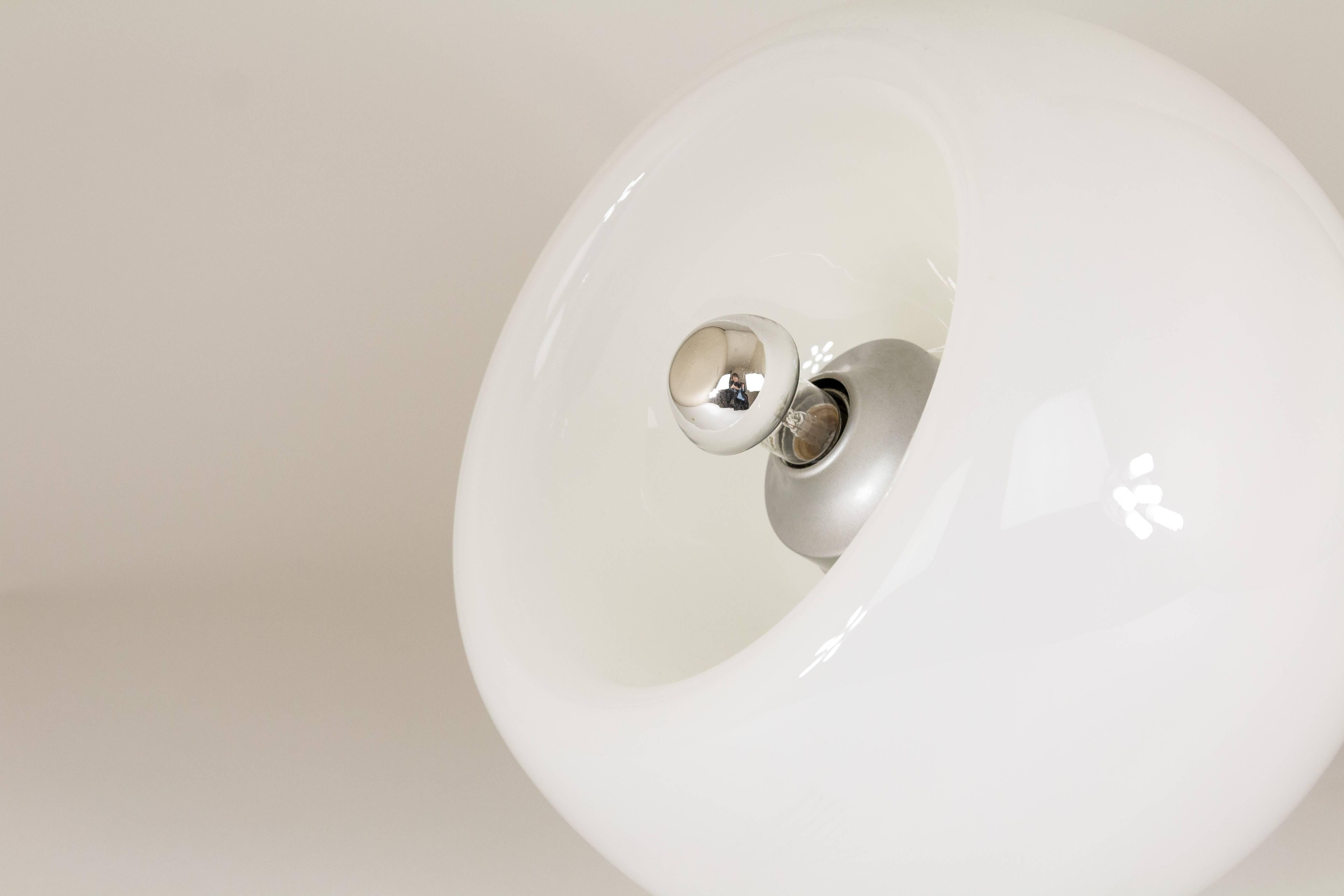 Hand blown glass lamp named Vacuna, designed by Eleonore Peduzzi-Riva for Artemide in 1968. The lamp can be used both as a floor and a table lamp.

This one-piece hand blown glass globe is partially opaque white and partially transparent. The