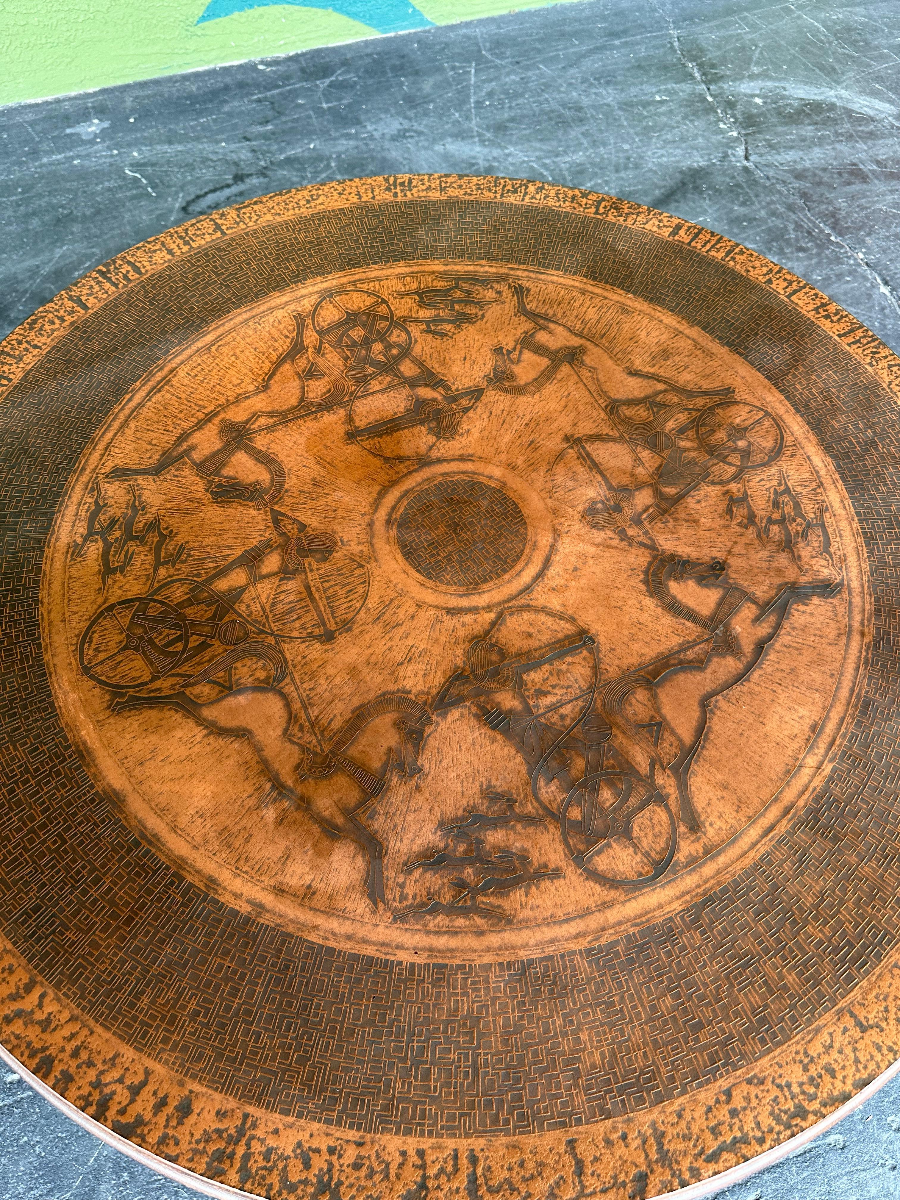 Vad Trevarefabrikk Norvège Table basse ronde moderne du milieu du siècle avec plateau en cuivre martelé et gravé dans un motif égyptien, reposant sur un cadre en hêtre teinté foncé avec une base de style X. En bon état général, avec une légère