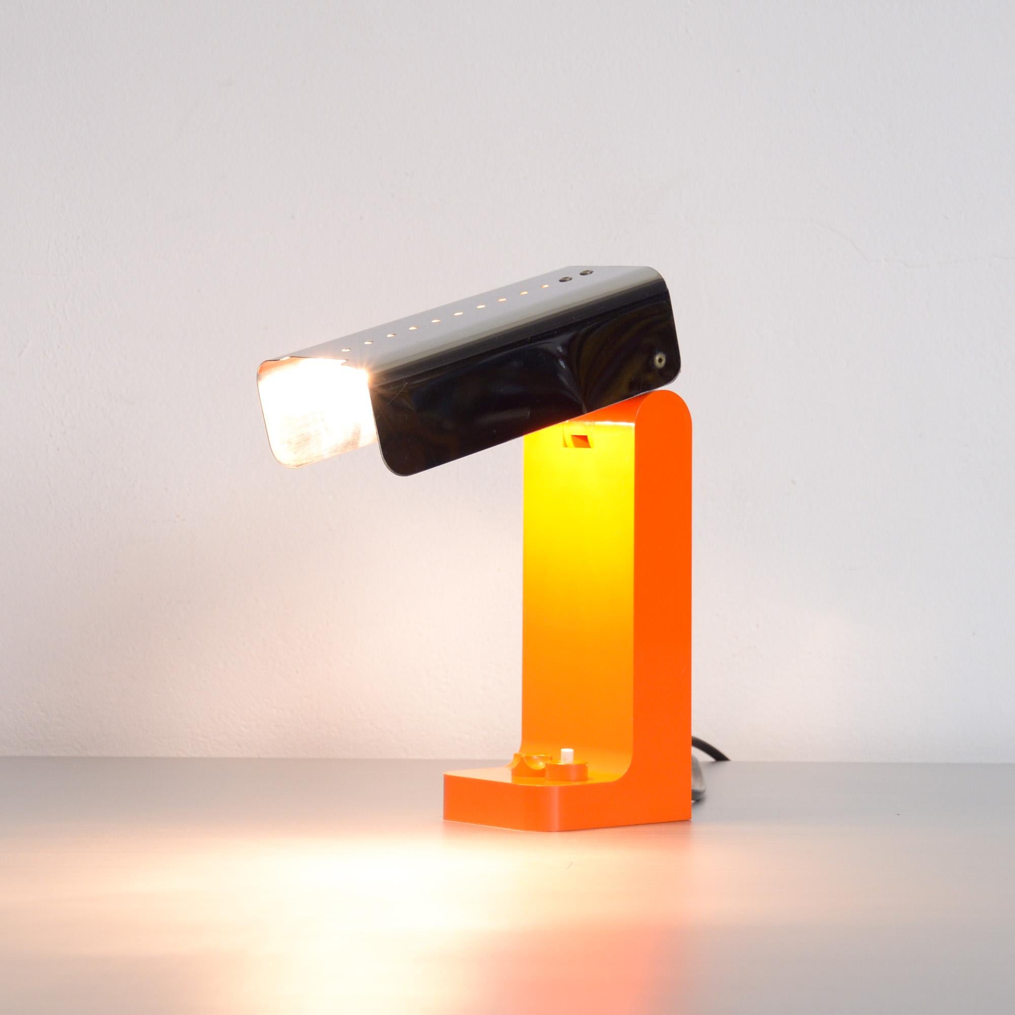 The Vademecum desk or table lamp was designed by Joe Colombo in 1968 and edited by Kartell in 1969.
The orange base is made of Cycolac plastic and the lampshade is made of stainless steel. Both parts are connected with a pole that holds the