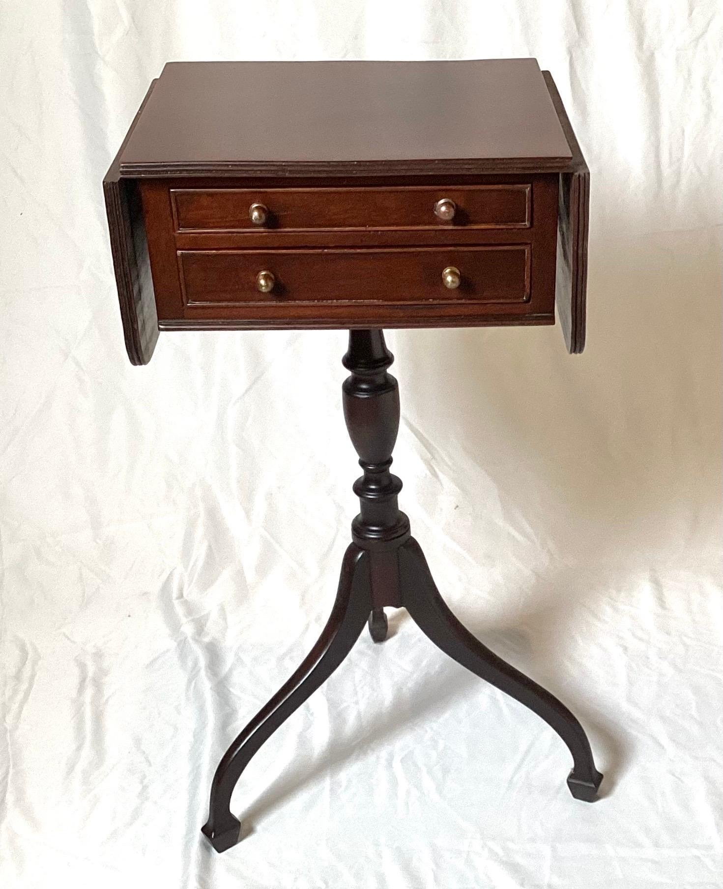 A diminutive Hepplewhite style antique drop leaf side table.  The table with spider leg pedestal form,  with two slim drawers at the front.  The table is a perfect pull up table for a traditional style room.  25 inches tall, 13 inches wide, 10.5