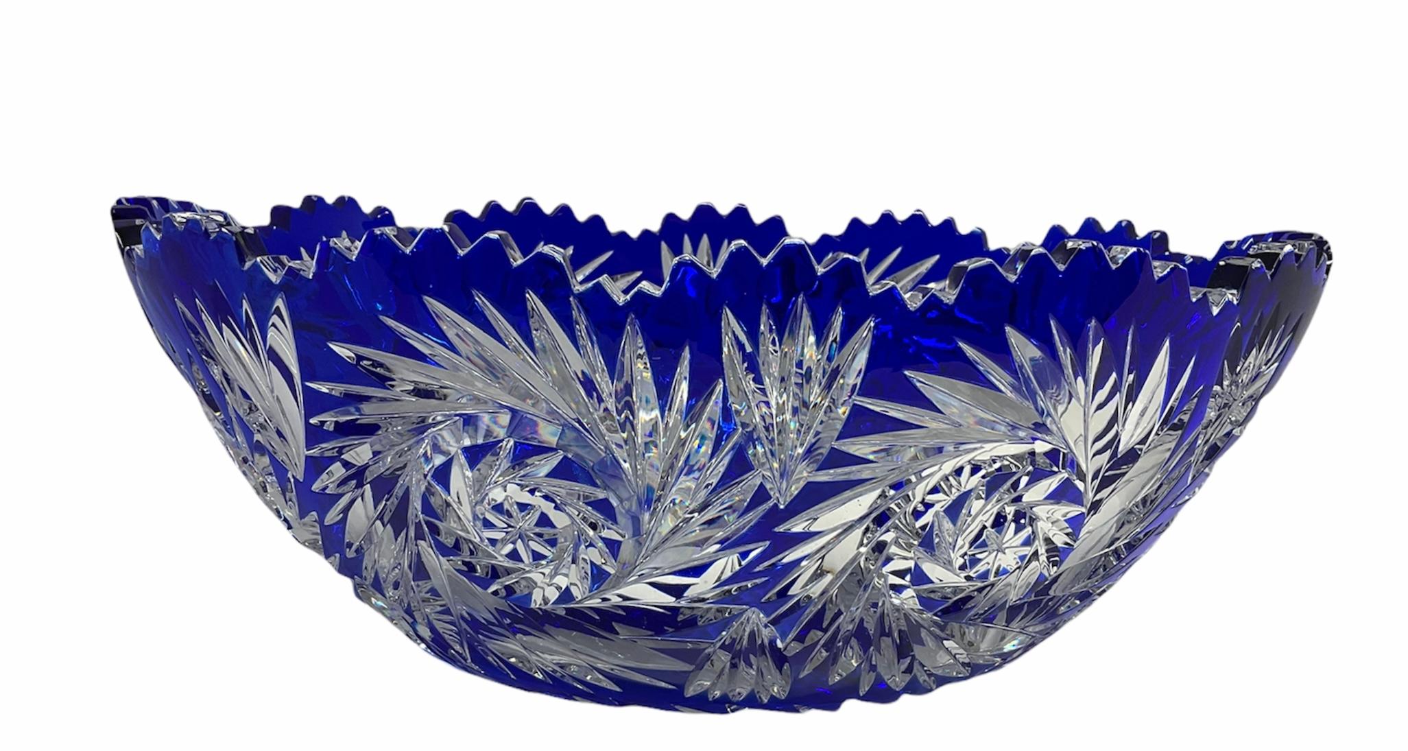 This is a Val Saint Lambert royal blue cut clear crystal large oval bowl. It is depicting one large buzz in the center and a pattern of more big buzzes alternated with fans around it. Its rim is scalloped.