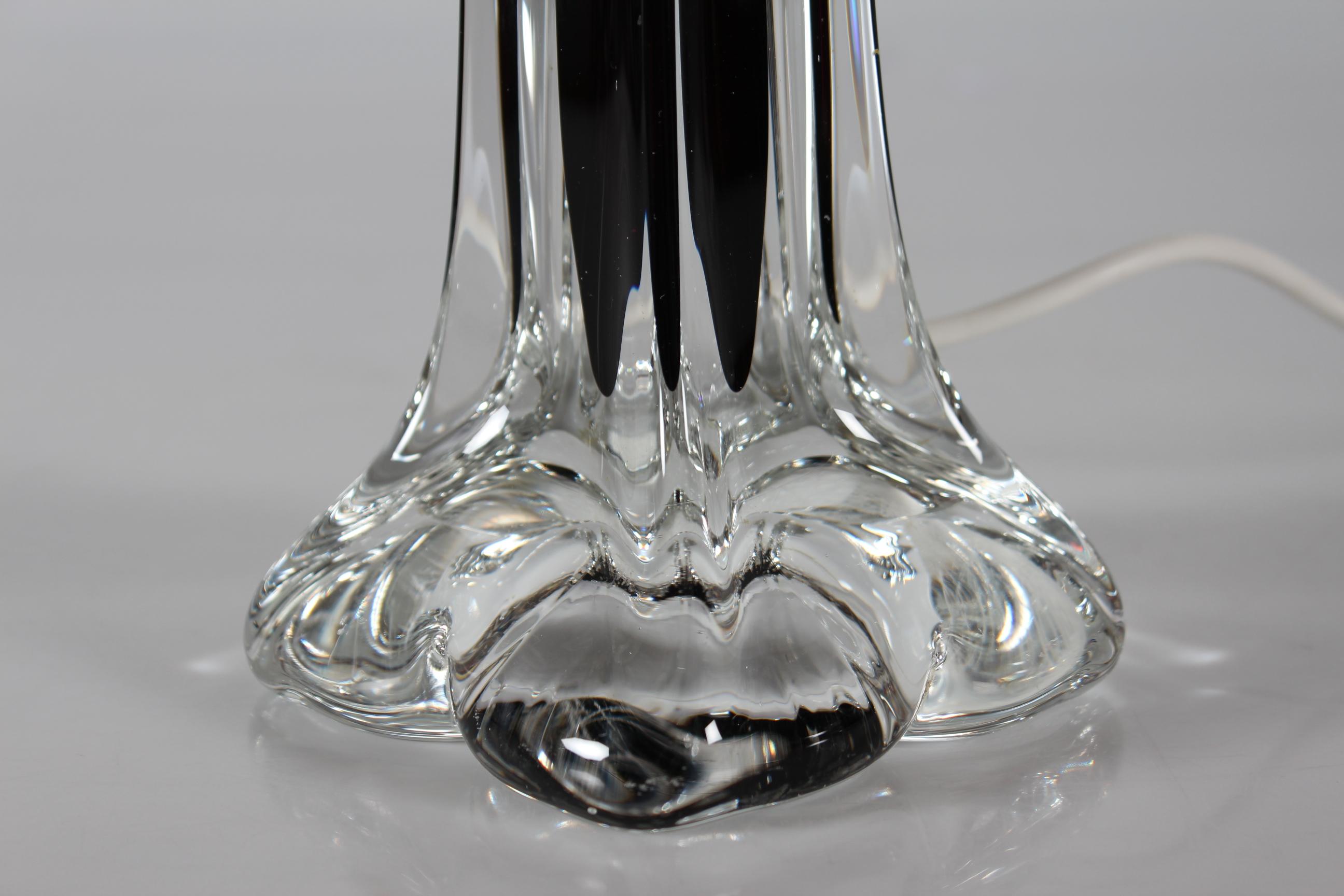 Lampe de table Paul Kedelv réalisée par Flygfors dans les années 1960. 

La base artistique de la lampe, haute et élancée, est faite de cristal clair avec un noyau de couleur marron/aubergine foncé.

Vous trouverez également un nouvel abat-jour
