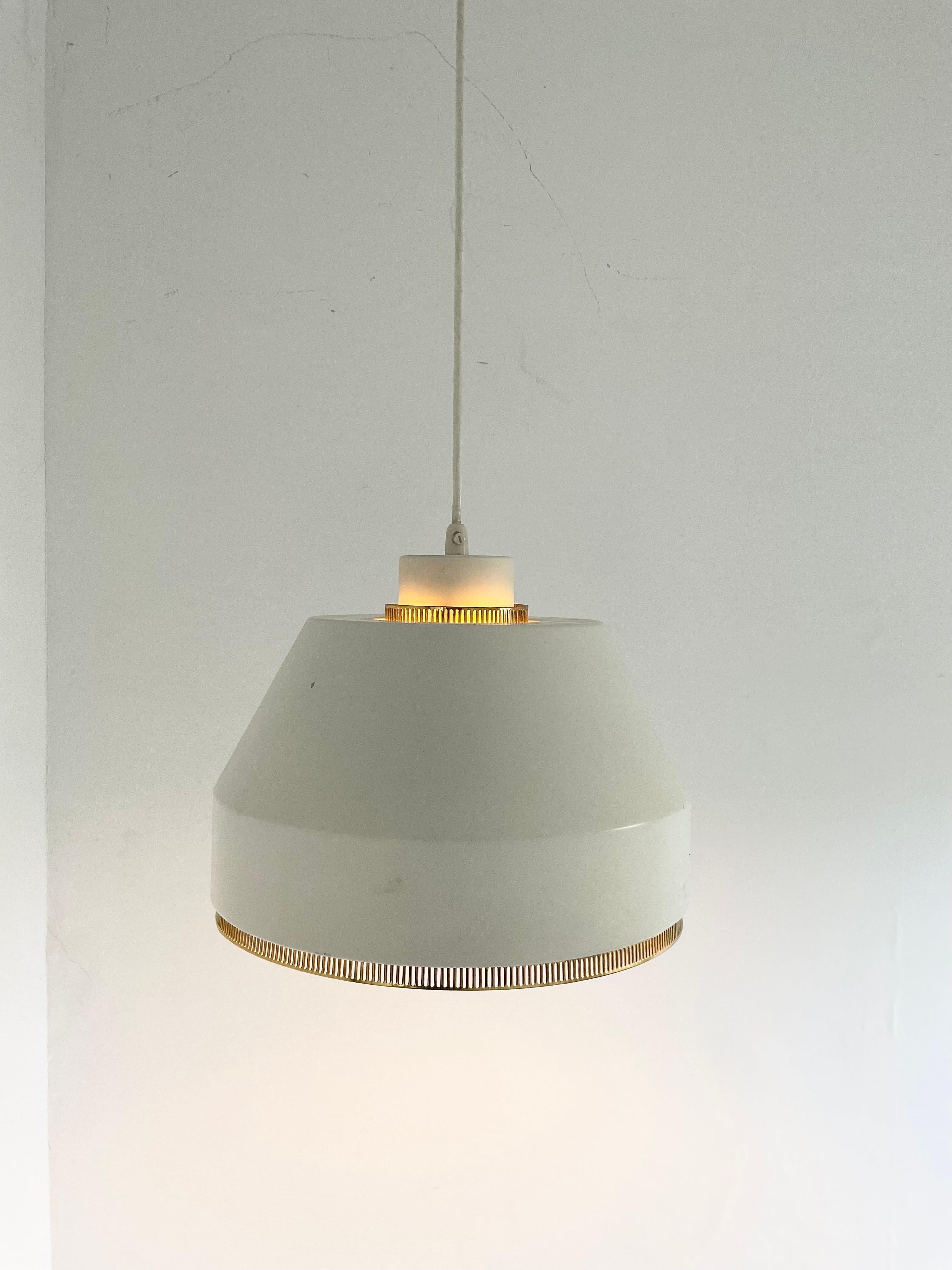Pendant light 'AMA 500' with brass details by Aino Aalto, designed 1941. This piece was made by Valaistustyö of Finland.

The design features an aluminium shade painted in old white (warm tone) with delicate brass details. The open shade provides
