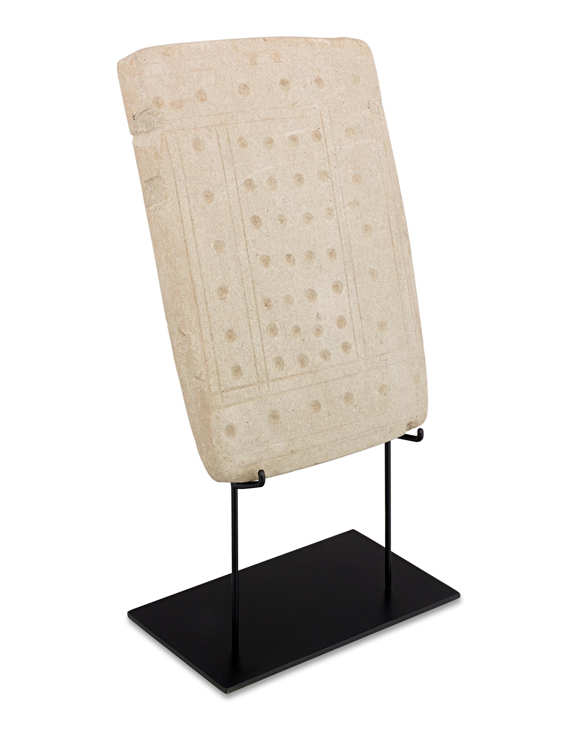 This light grey limestone slab, adorned with drilled dots, is a mysterious and intriguing artifact attributed to the Valdivia people, one of the earliest settled cultures in the Americas. The Valdivia culture thrived on the Santa Elena peninsula in
