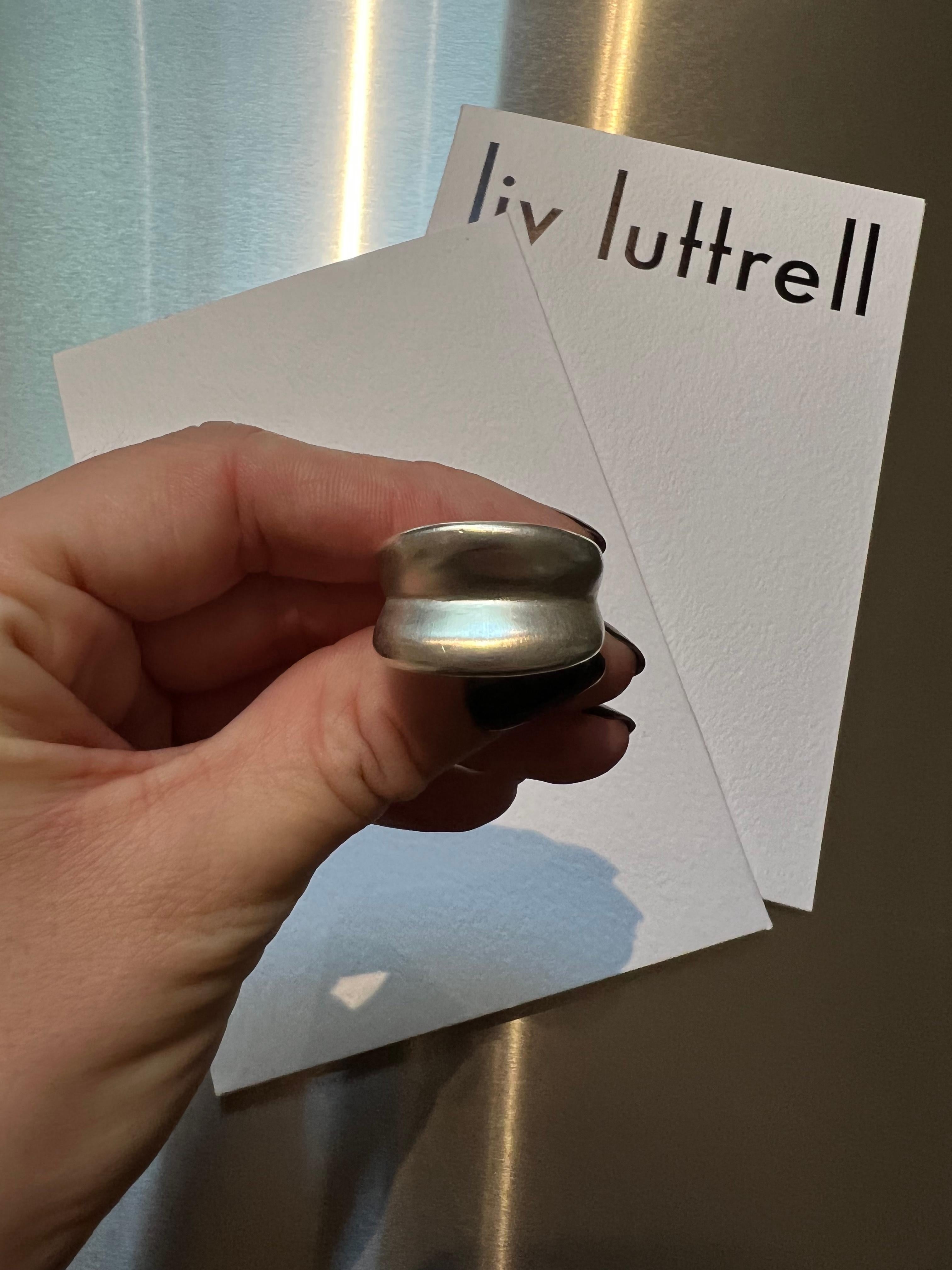 Liv Luttrell 
Silver Folde ring 2023


Details 
Limited edition of 30-piece
Silver
Mixed satin and high-polished finish
Made in London 


Customisation 

As this design is handmade to your order, Liv is able to customise the material choices