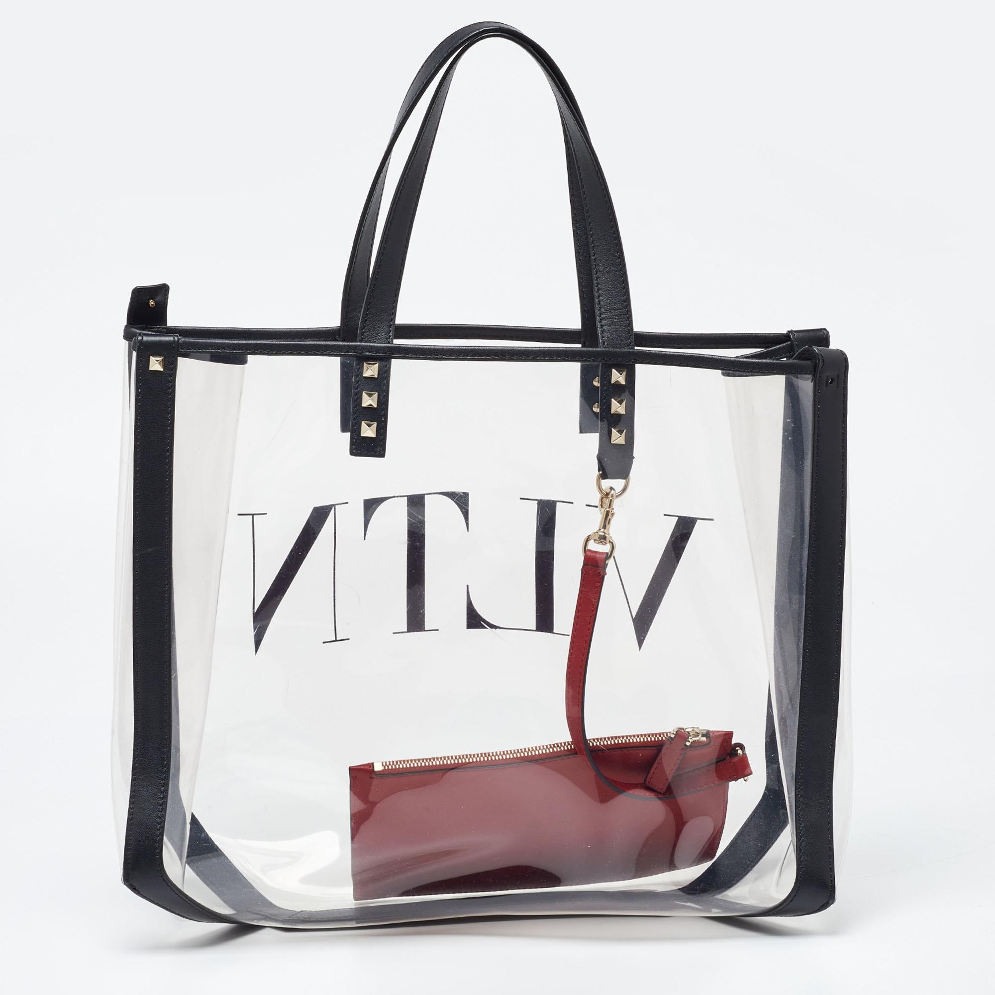 Now get your shopping done hassle-free with this spacious transparent Valentino tote. Crafted from PVC and leather, it features top handles, Rockstuds in gold-tone metal, and a red internal clutch. The VLTN logo on the front gives it a signature