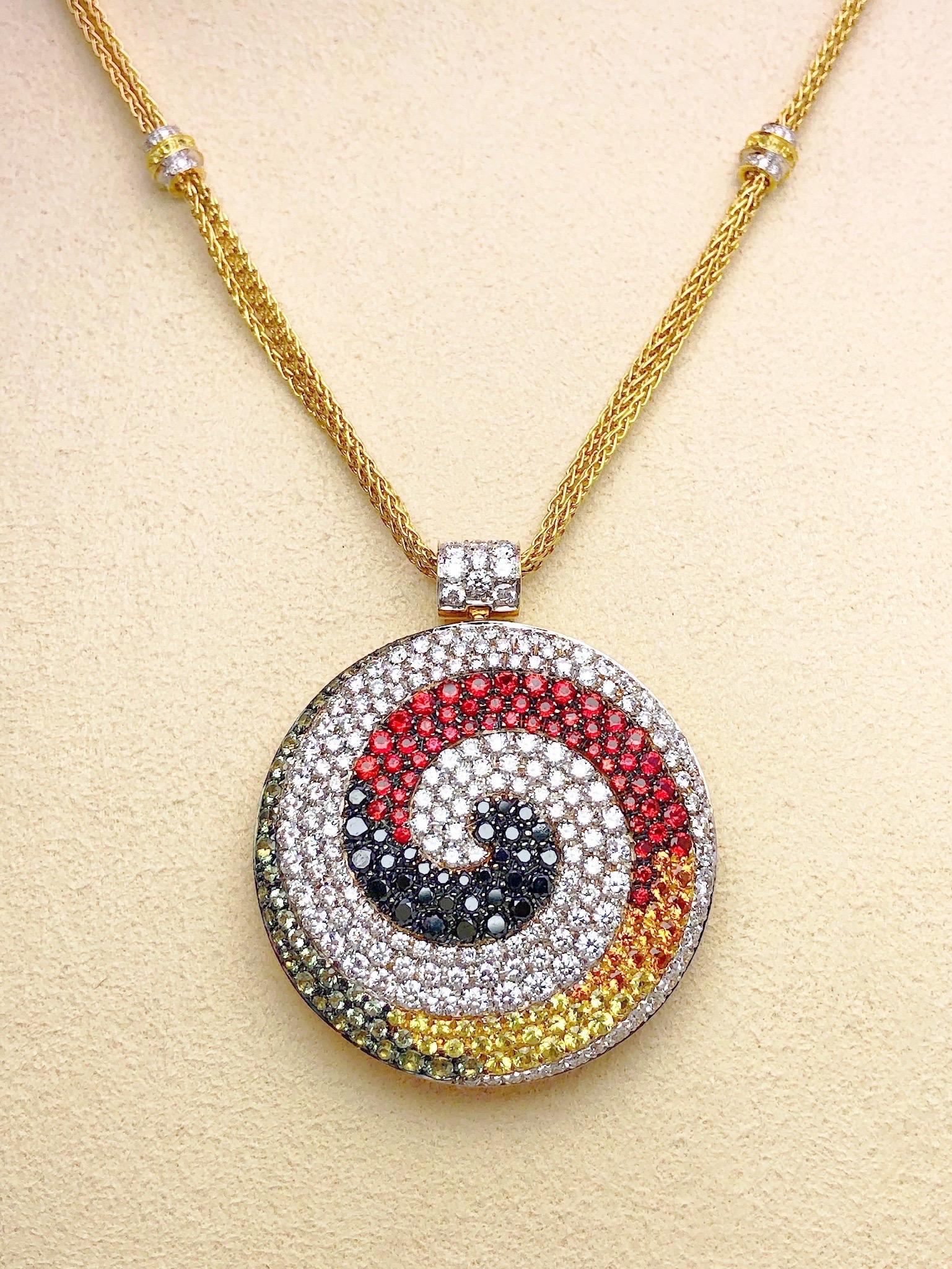 Ce collier a été conçu par Valente de Milan, en Italie. Le grand pendentif circulaire est serti dans un motif tourbillonnant de diamants ronds brillants blancs et noirs et de saphirs multicolores dans des tons de jaune, orange, rouge et vert clair.