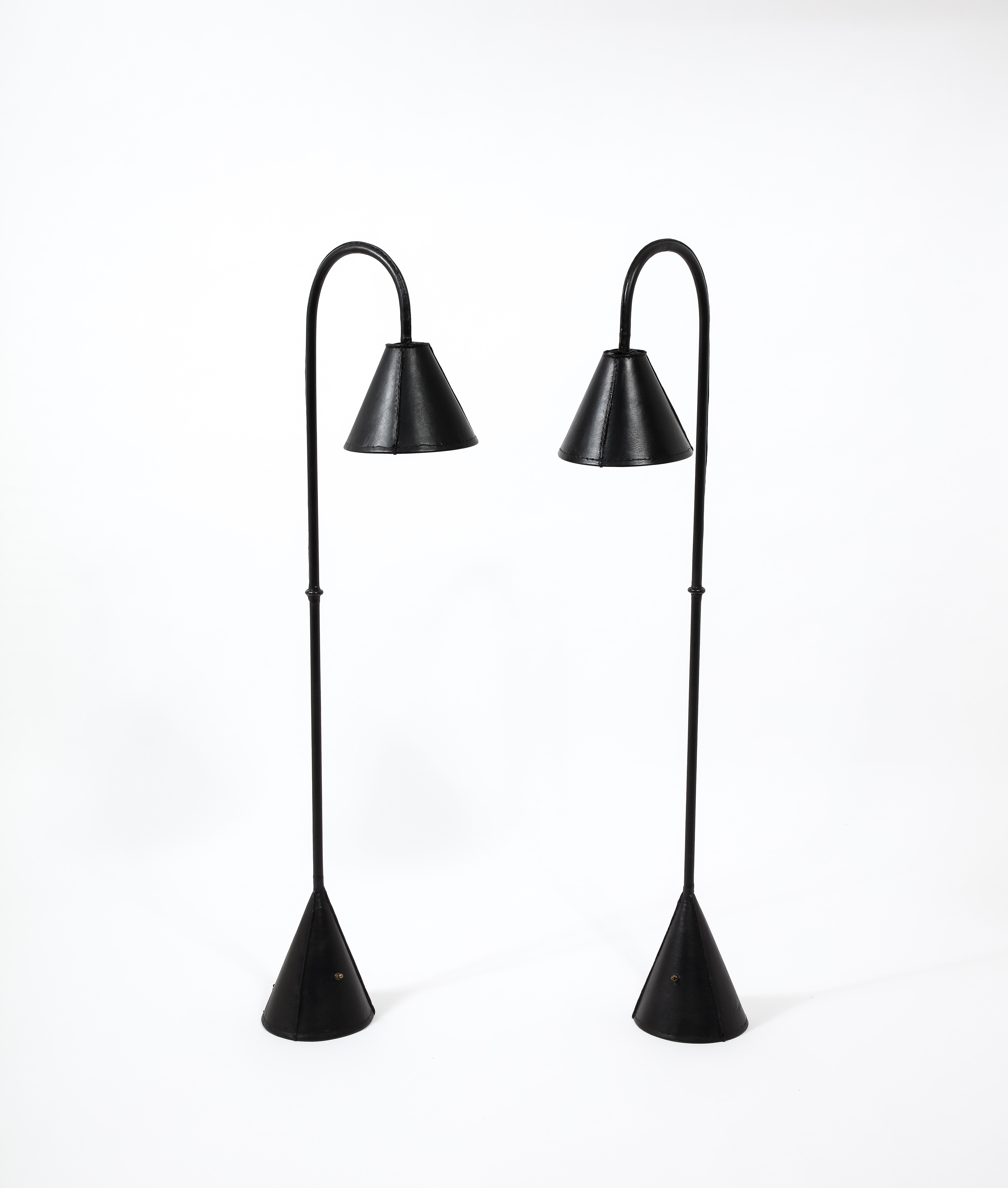 Matched pair of black leather stitched floor lamps in excellent condition with weighted bases. Rewired.
