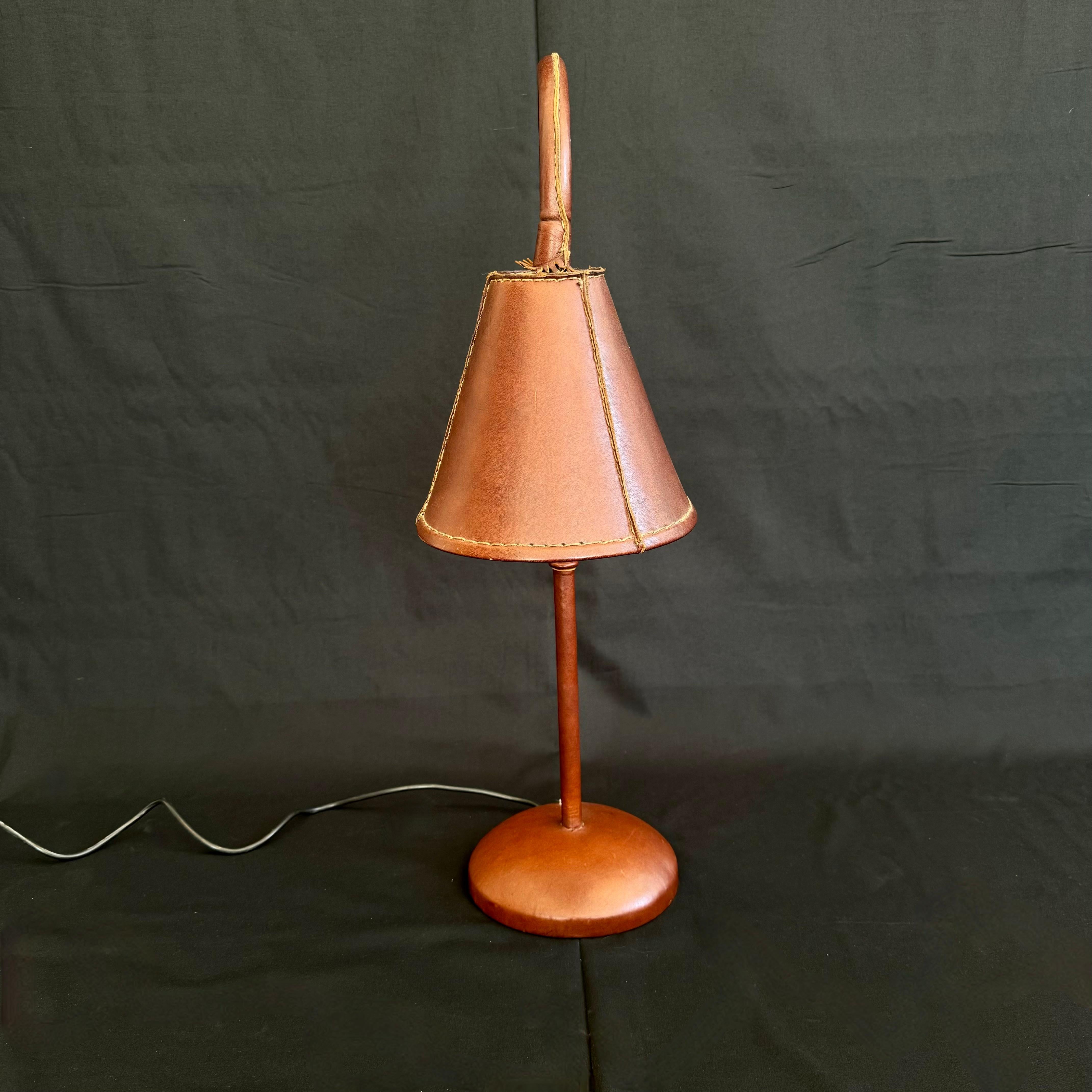 Handsome leather arched table lamp by Spanish design house, Valenti. Based in Barcelona and founded over 200 years ago, Valenti has deep roots in high end furniture and elegant designs. Made in the 1970s this table lamp is completely wrapped in an