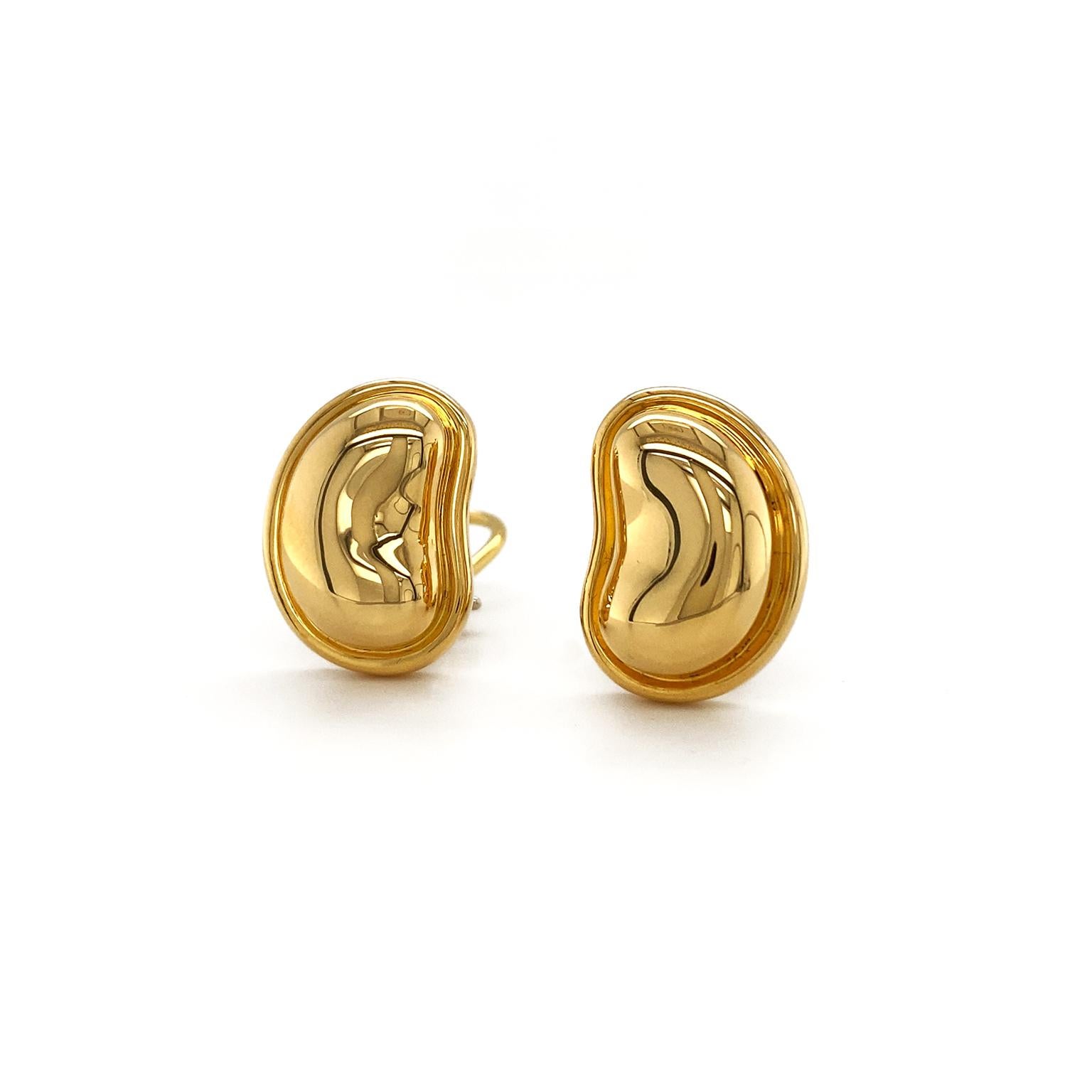 Designed with the unique sculpt of beans in mind, these polished 18k yellow gold earrings scintillate. The overall curve of the beans faces inward and are bezel set. Clip-backs attach the ears to the earrings, which measure 0.54 inches (width) by