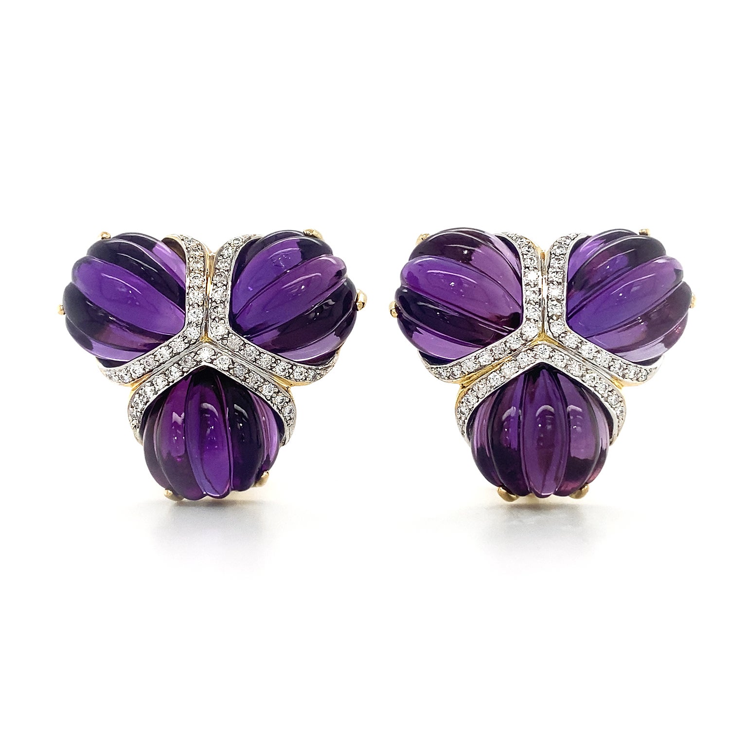 Grandeur is the result of pairing amethyst and diamonds. Intense violet and soft lilac hues of amethyst are heightened by their carved fan shapes. Three fans are joined together by their tapered tips, which are trimmed with a triangular arrangement