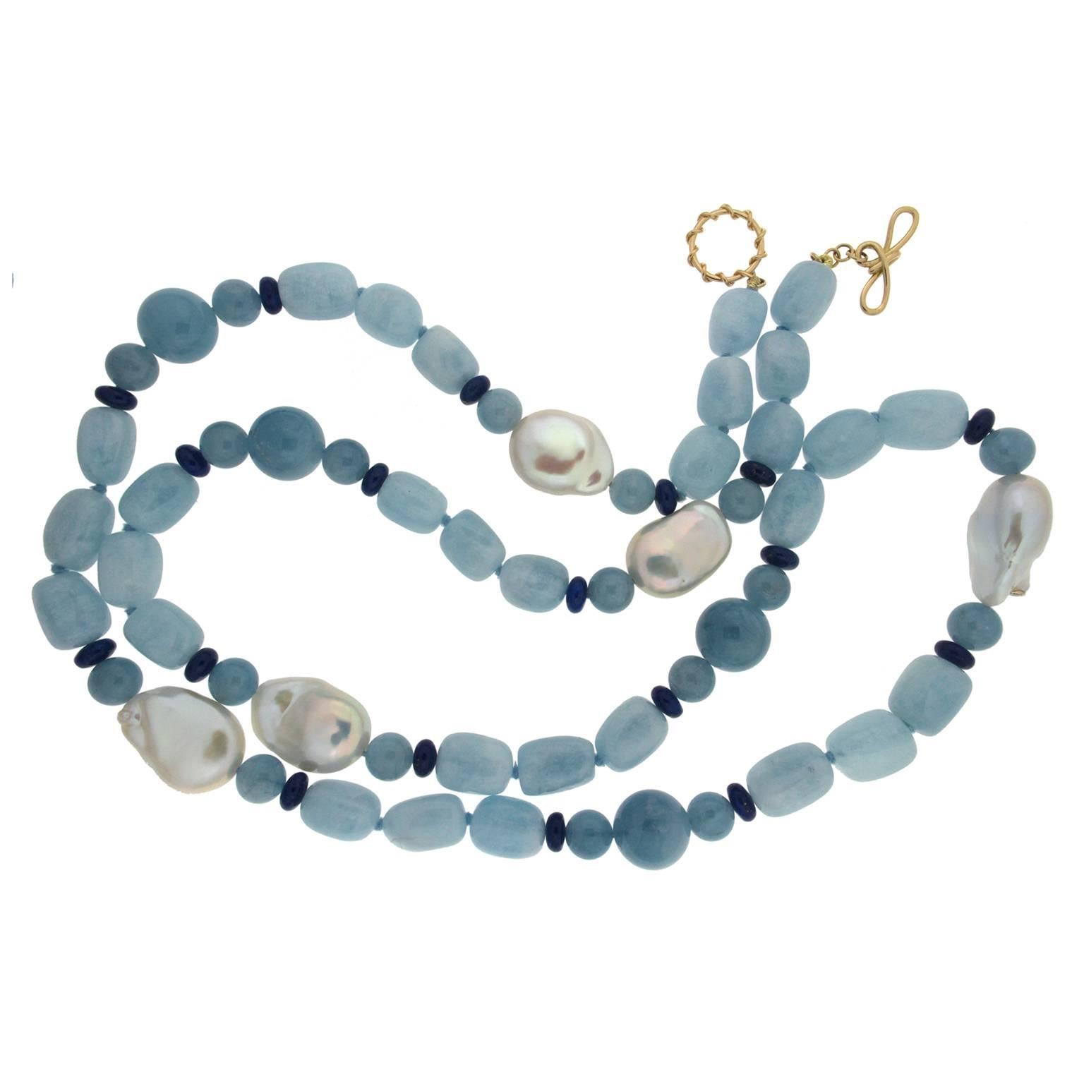 Cool-toned gems evoke the serenity of the sea. Aquamarine is the anchor of this necklace, featuring carved oval and globe beads. Lapis lazuli rondellle beads emphasize the blue hues, while freshwater baroque pearls disband throughout the necklace