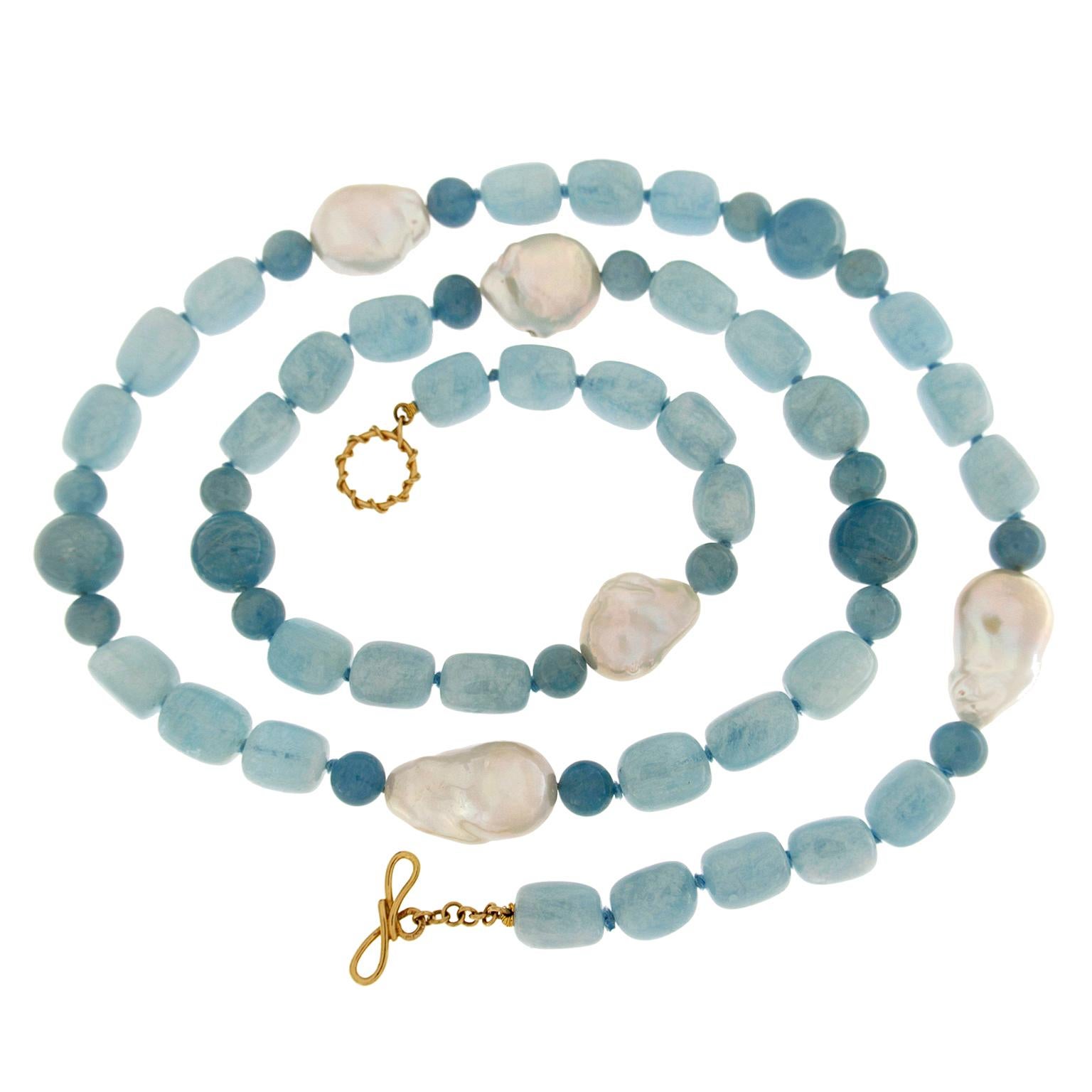 An array of blue displays the varied shades of aquamarine. The pattern begins with five irregularly shaped beads of pale blue. This follows with a baroque white pearl, emitting its satin radiance, in between two roundels of blue-gray. Next, three