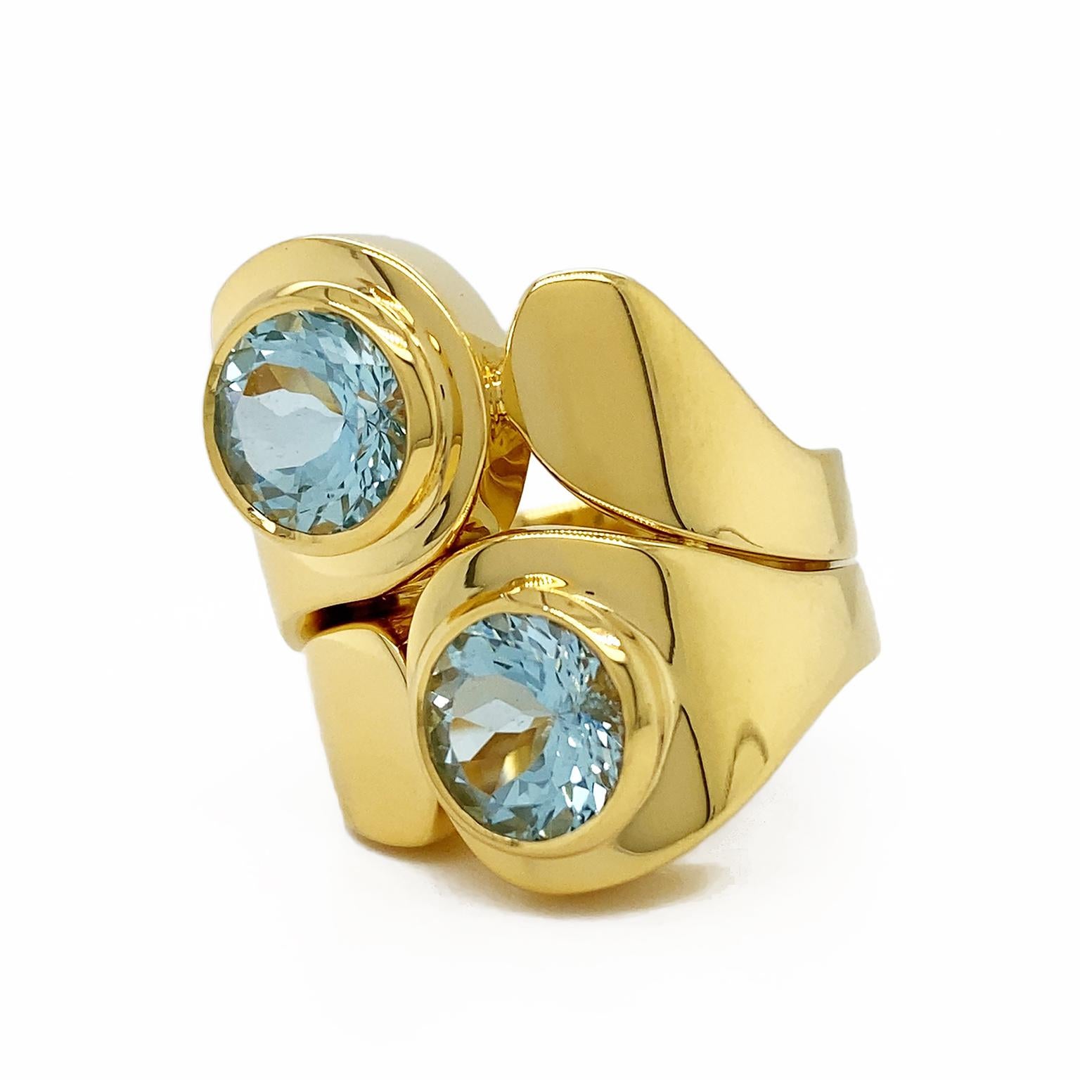 Contrast combines with the coruscating glow of aquamarine. Two tapered 18k yellow gold bands are joined together. As the crowning touch, bezel-set aquamarines are on the broadest ends for a sparkling enhancement. The ring measures 0.87 inches