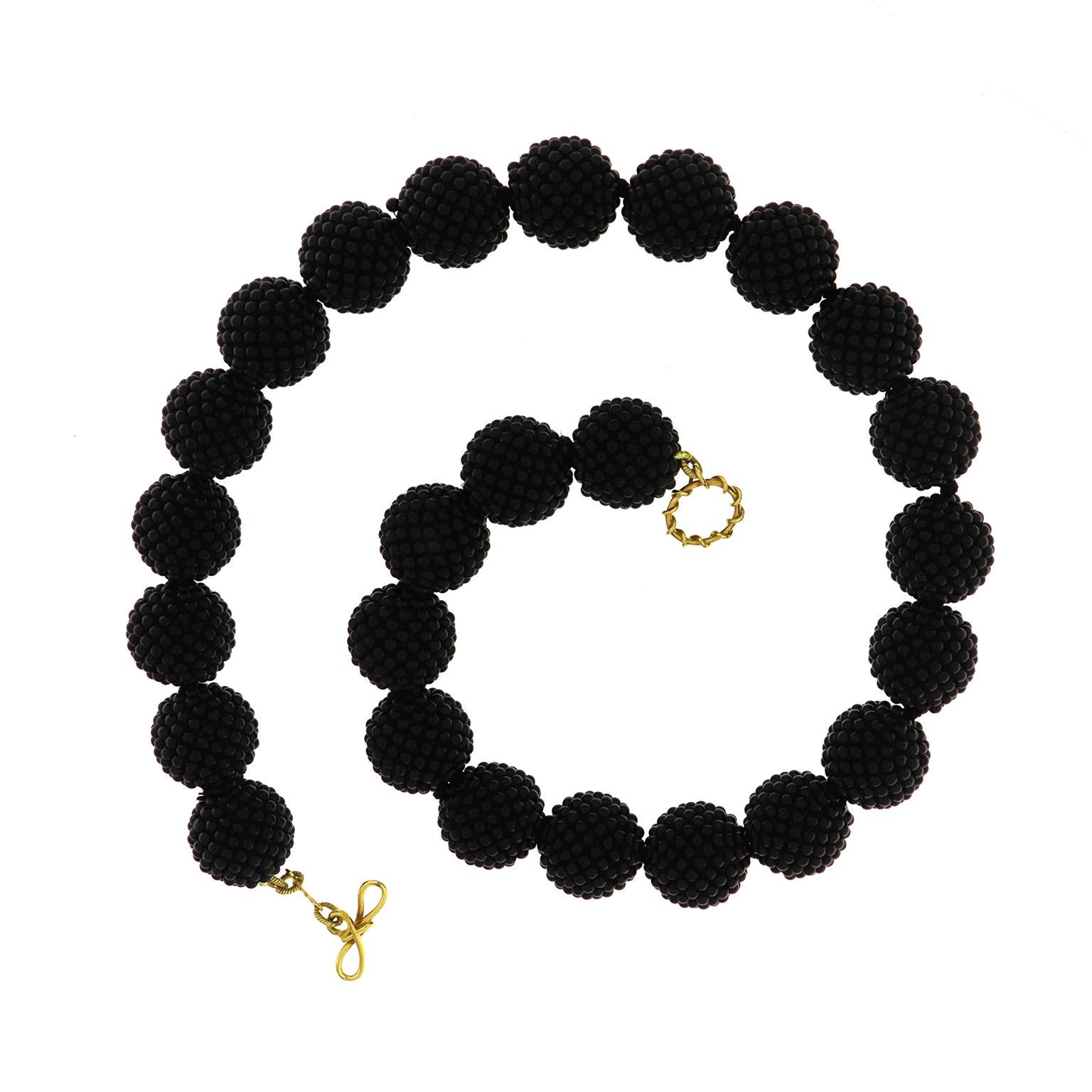 Valentin Magro Black Onyx Woven Ball Necklace boast complex beads. Tiny black onyx pieces are woven into balls 18mm large, creating a textured surface. There are 25 balls in the necklace. An 18k yellow gold knot and toggle clasp fastens the