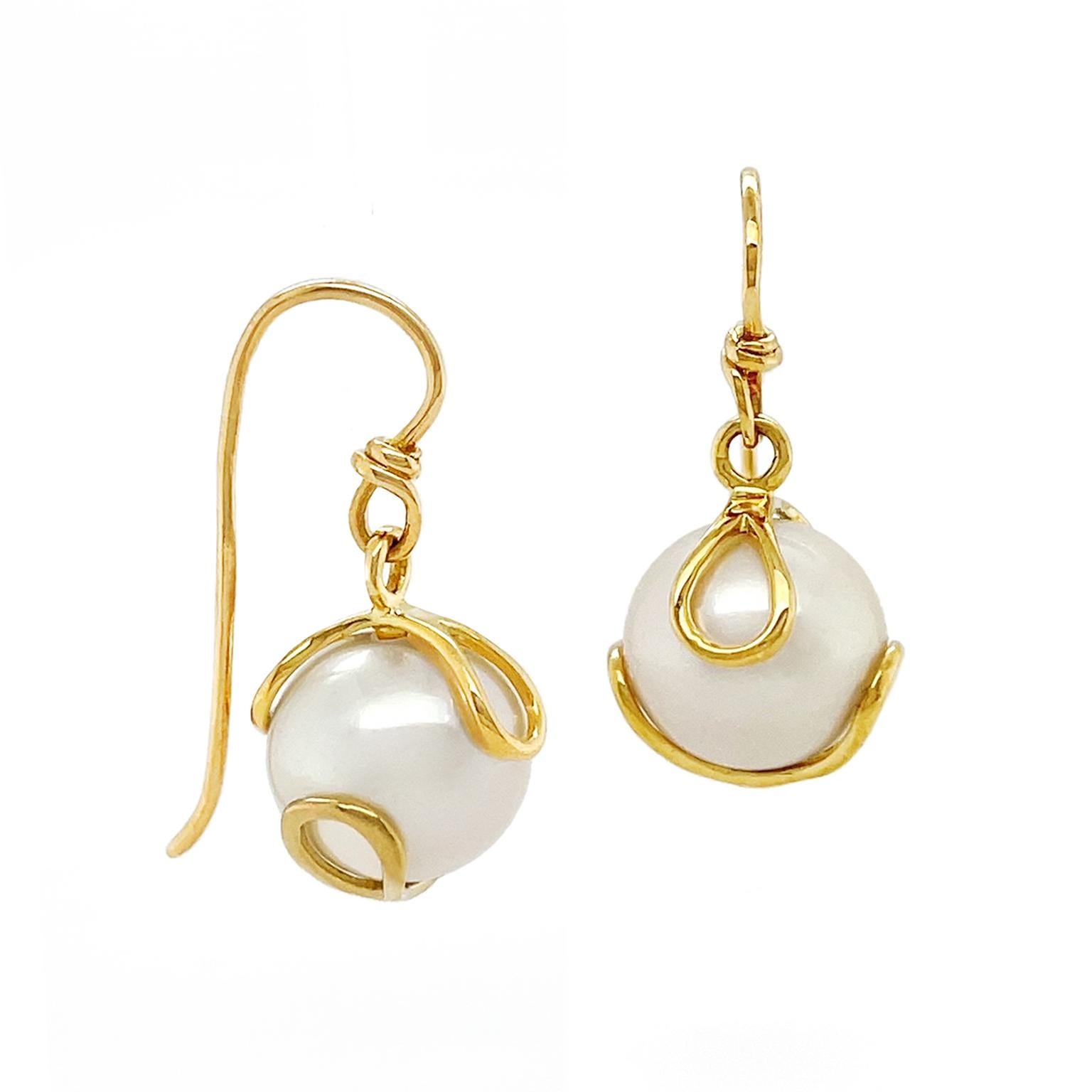 The prismatic beauty of a fresh water pearl is showcased in these earrings. 18k yellow gold loops bring warmth while sheltering the pearl, capturing the light in a variety of subtle colors. French hooks complete the earrings, which measure 0.48
