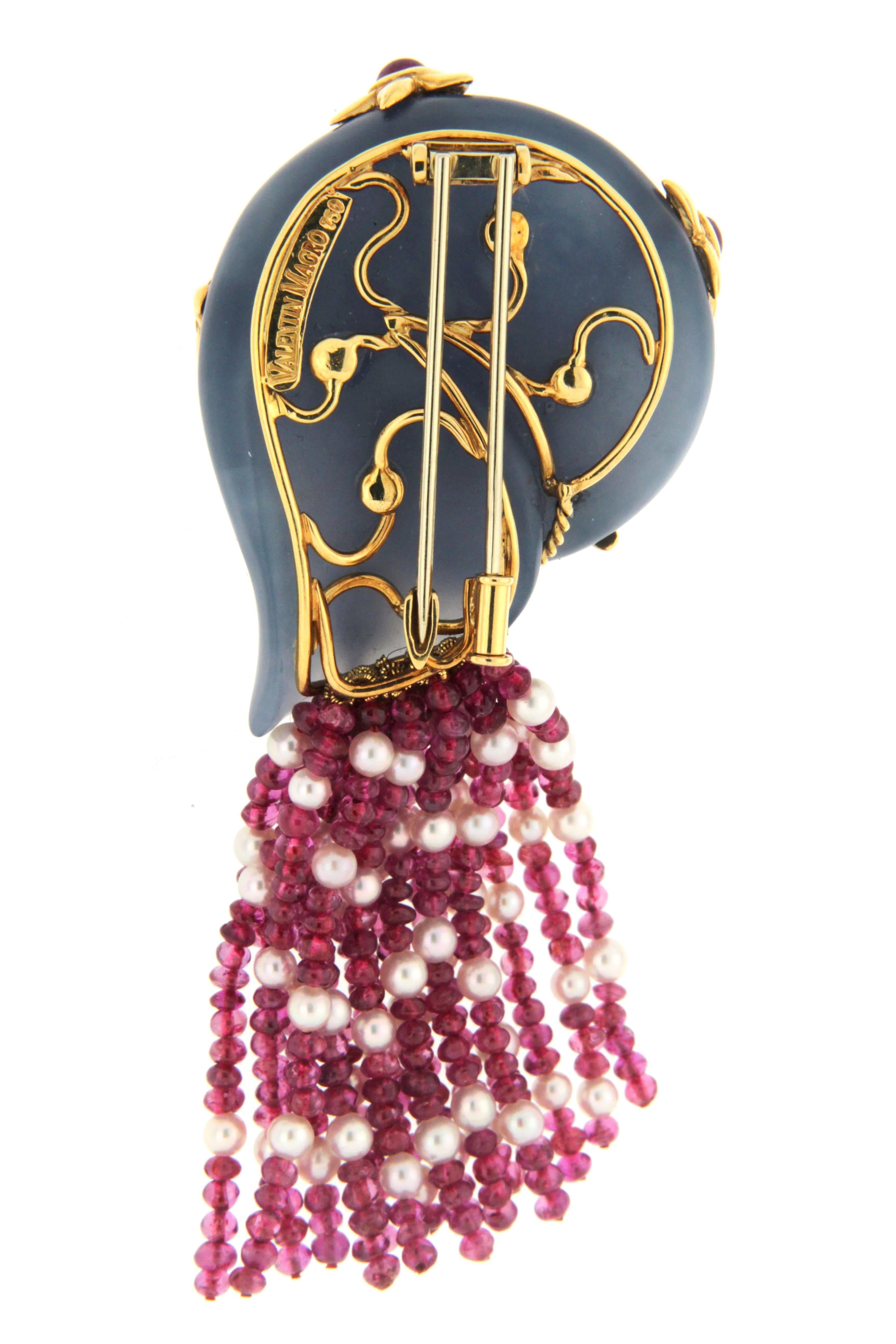 The snail brooch evokes an oceanic spirit. Soft blue chalcedony is carved as the shell. The 18k yellow gold braid coils along the center. The coil is adorned with round brilliant cut diamonds set in miniature spirals. Enhanced with round rubies, the