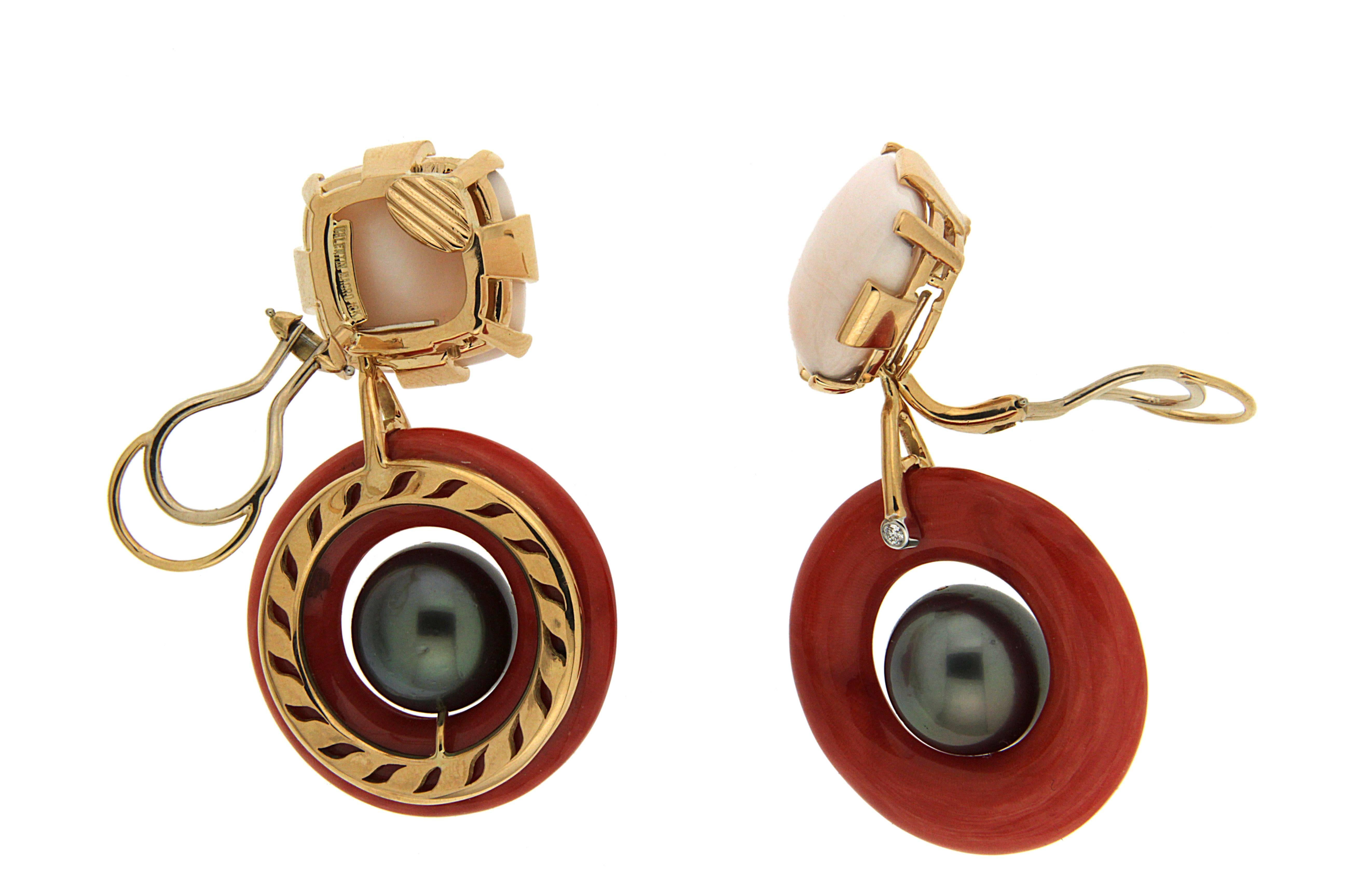 These drop earrings created by Valentin Magro, have a subtle marine motif. The base features pale pink coral carved into cushions. Bars of 18k yellow gold secure the gem. The lowermost gold piece also supports a dark coral ring with a Tahitian pearl