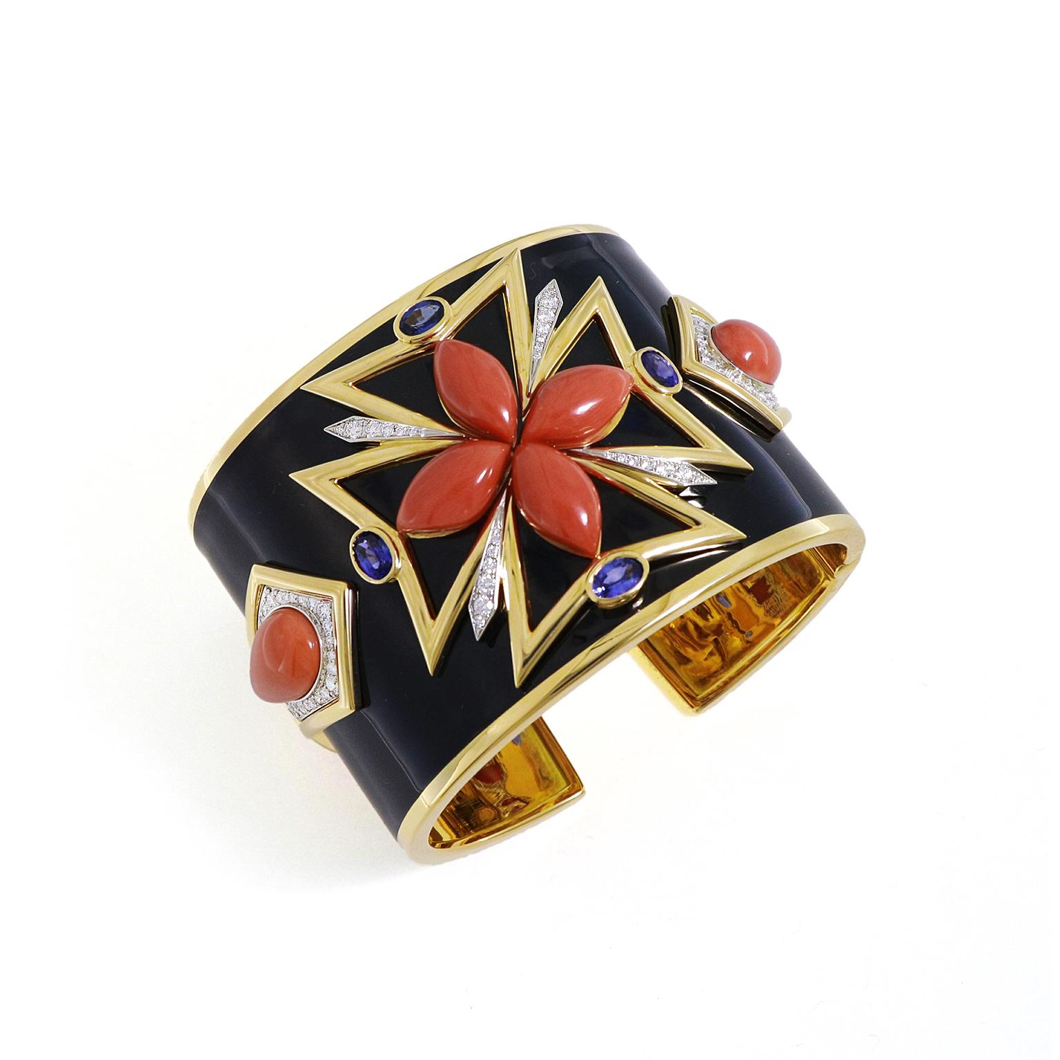 Daring colors of gems give this bracelet a striking design. An 18k yellow gold cuff is covered with black enamel, allowing the gold to glint on the top and bottom. In the middle, precious metal creates a Maltese cross with oval sapphires accenting