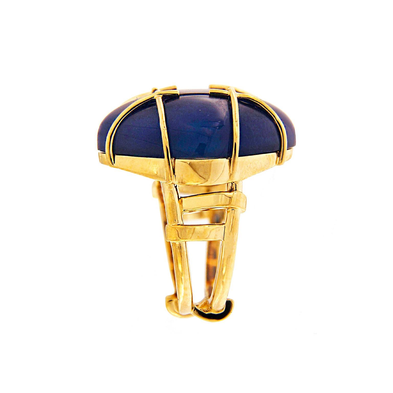 Blue agate is the lucent peak of this ring. Carved into a square cabochon of 31.5 carats, the chalcedony is rotated on its side to form a rhombus. Sleek 18k yellow bars wrap over the gem in a crisscross pattern, for added color and contrast. The