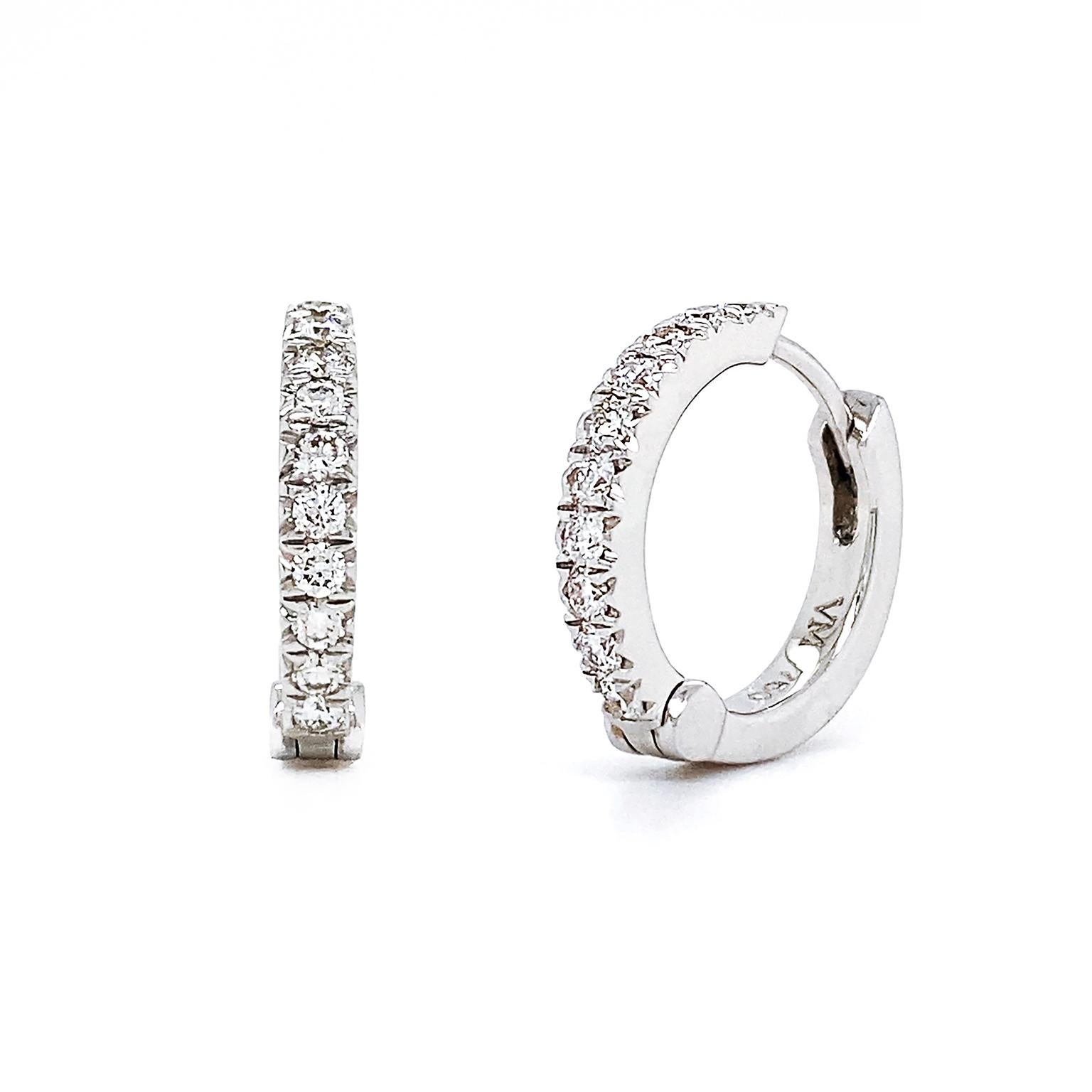 Diamonds produce a glistening light to these hoop earrings. 18k white gold hinged hoops are swathed with a row of brilliant cut diamonds, which total to 0.37 carats. A post and tube fastener secure the earrings, which measure 0.1 inch (width) by 0.6