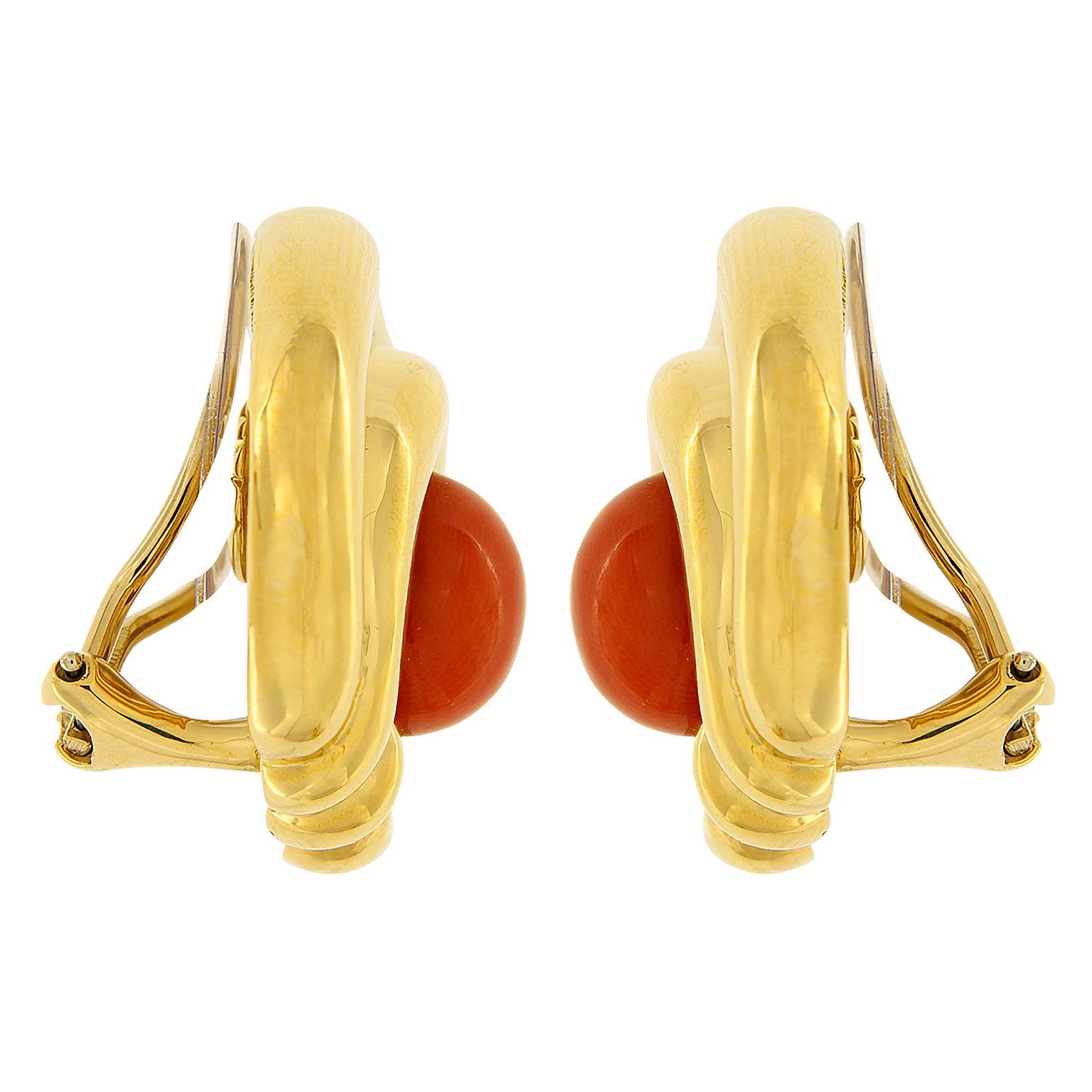 Coral and gold come together in these earrings created by Valentin Magro. In the middle is coral carved into 11mm by 9mm oval cabochons. Wrapping around the jewels are 18k yellow gold with an overhand knot on the bottom. The precious metal curves up