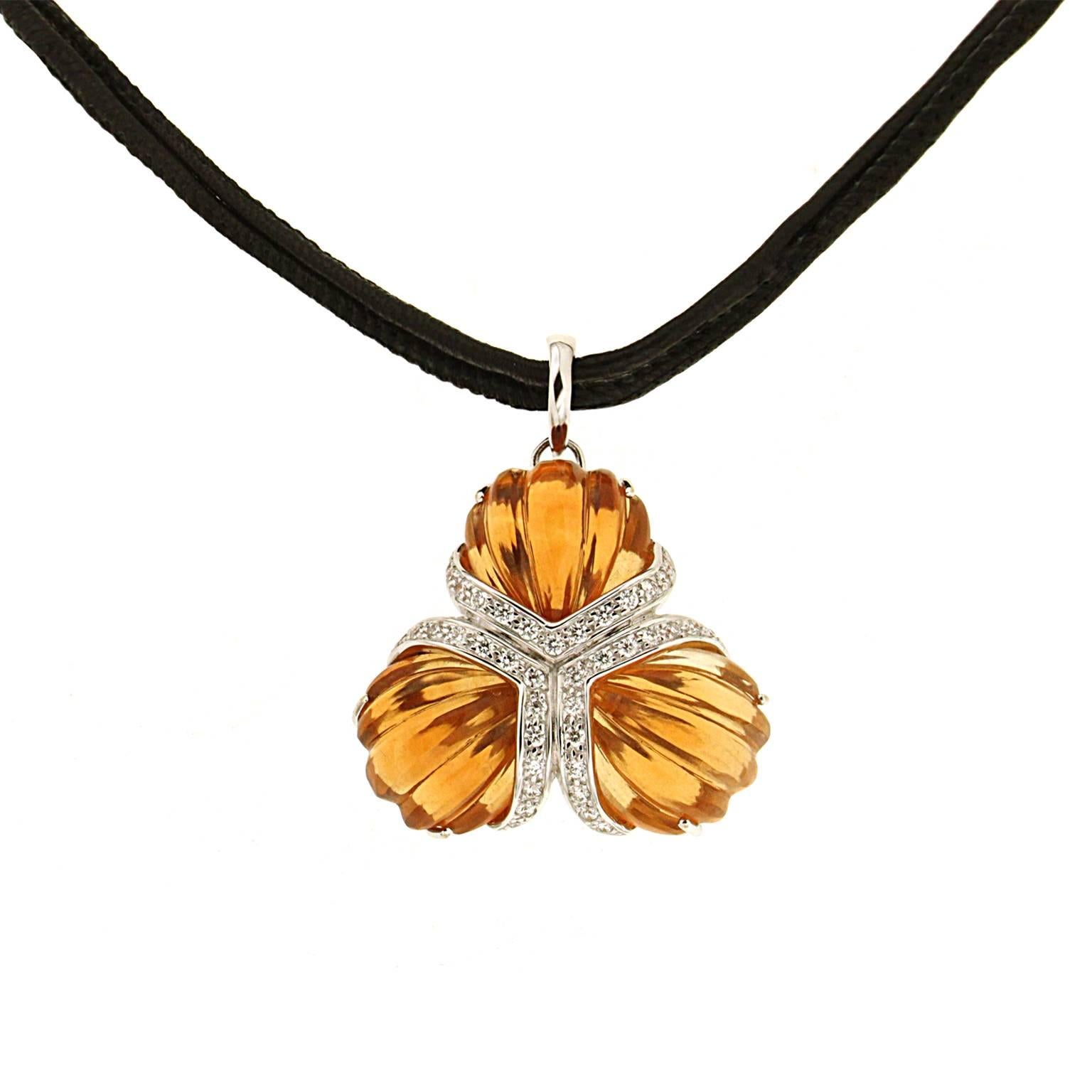 A fan motif is formed by three citrines carved into tapering ridges. They meet at their narrowest points, where the lower edge of each gem is adorned with round brilliant cut diamonds set in 18k white gold. The pendant measures 1.57 inches (length)