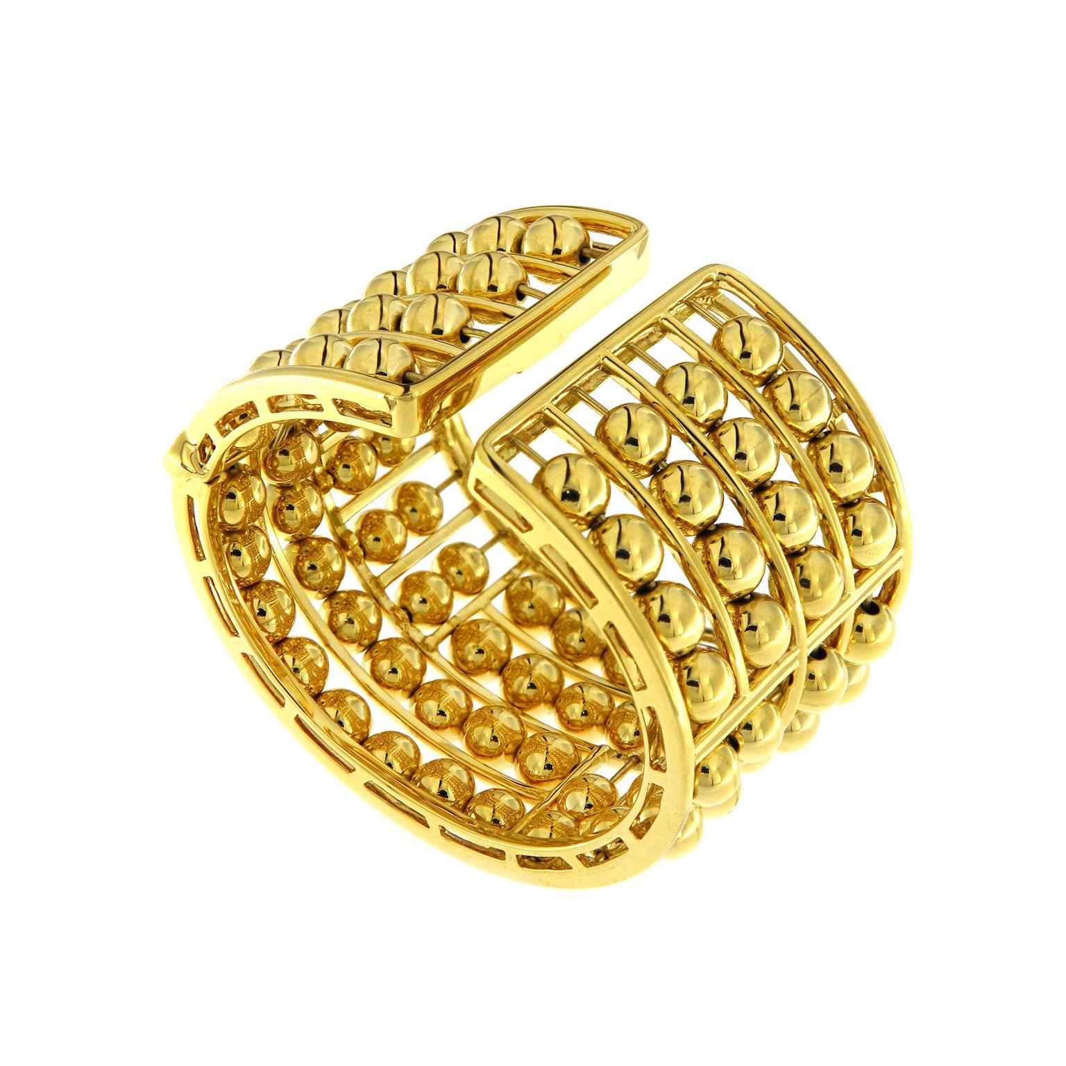 The reflective warmth of 18k yellow gold is the keynote of this cuff bracelet. Orbs of the metal are on coordinating wires of short and long rows. Some of the orbs are strung vertically alongside horizontal rows for visual interest. The result is