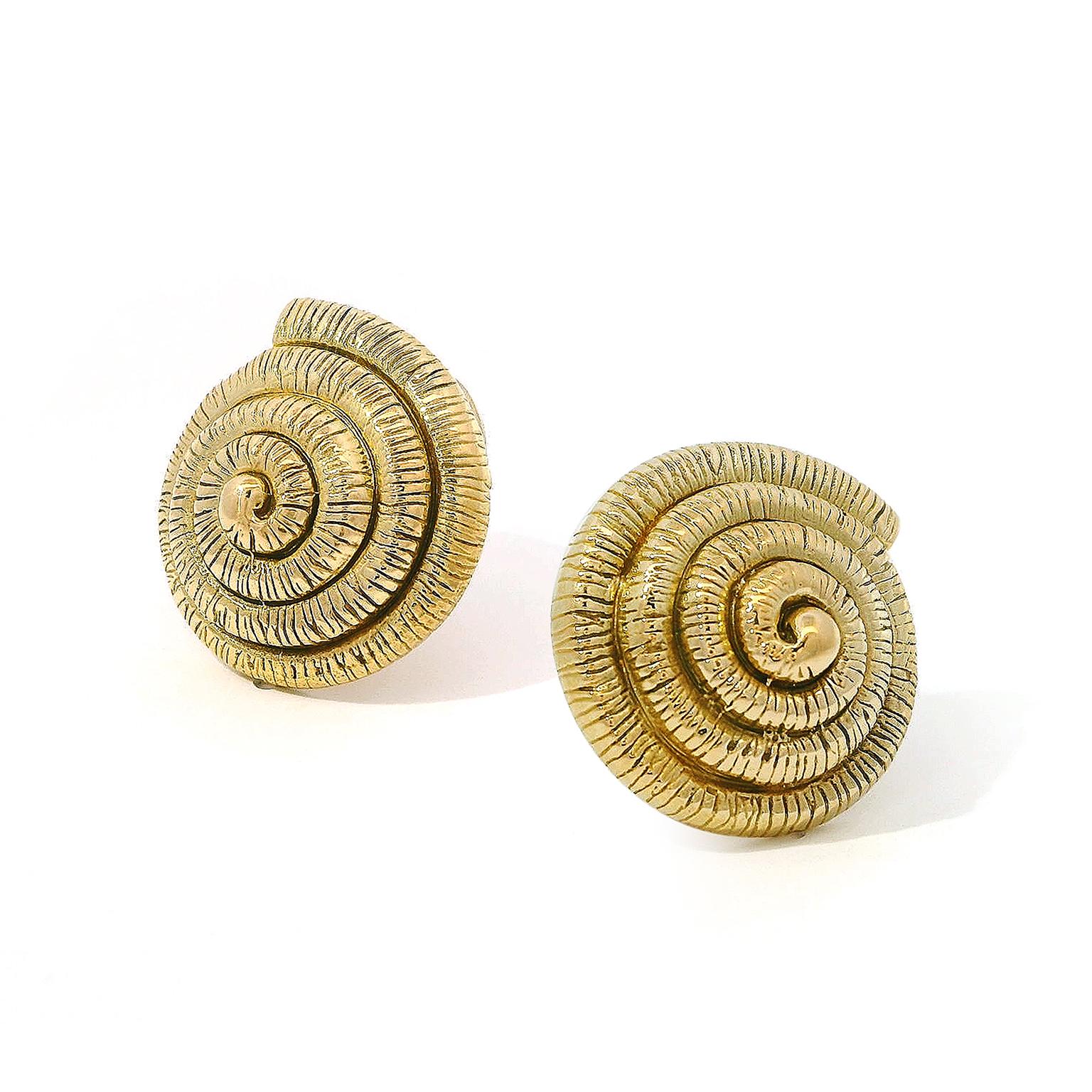 An oceanic glamour is created in gold. 18k yellow gold forms the shell of a nautilus, beginning with a strand that coils inward into a tight coil as the whorl of the shell. Parallel lines texturize the metal for definition, leaving the center sleek