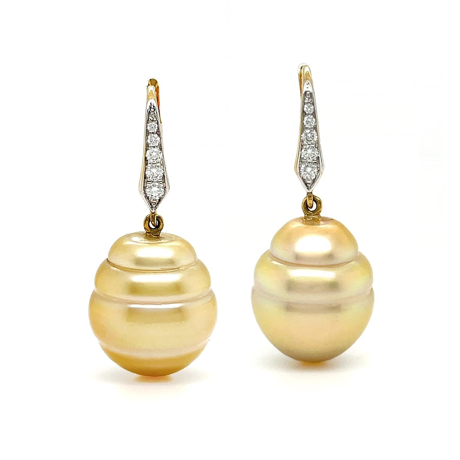 Teardrop Tahitian pearls in a rich golden hue mirror the light. These pearls, weighing 40.79 carats, have subtle circle detailing that adds dimension. Hanging from 18k yellow gold lever backs, the earrings also feature brilliant cut diamonds