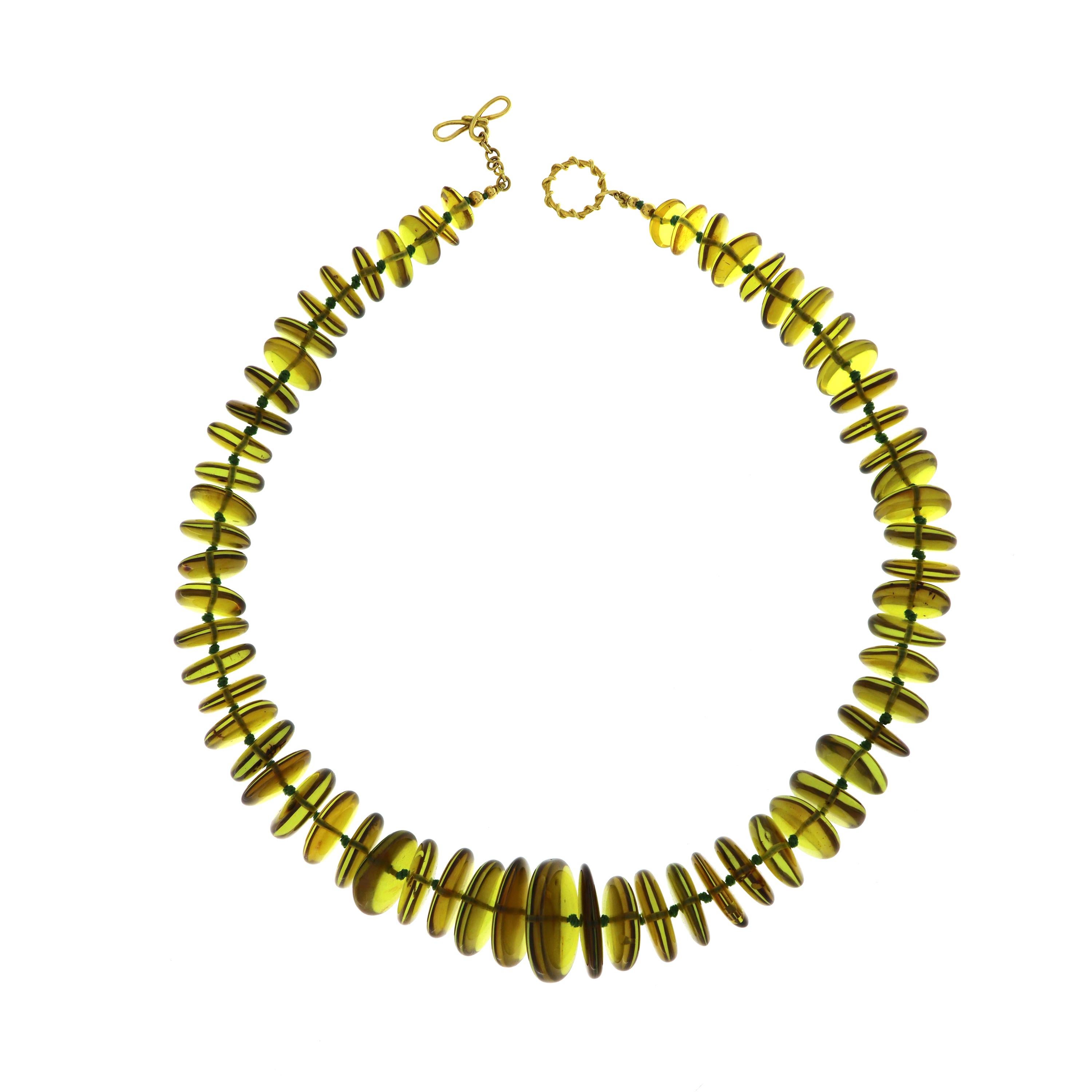 Valentin Magro Green Amber Disk Necklace seems to glow. Rather than the conventional golden brown, these gemstones showcase green hues. The jewels are carved into disks, with the smallest at the ends and largest in the center. An 18k yellow gold
