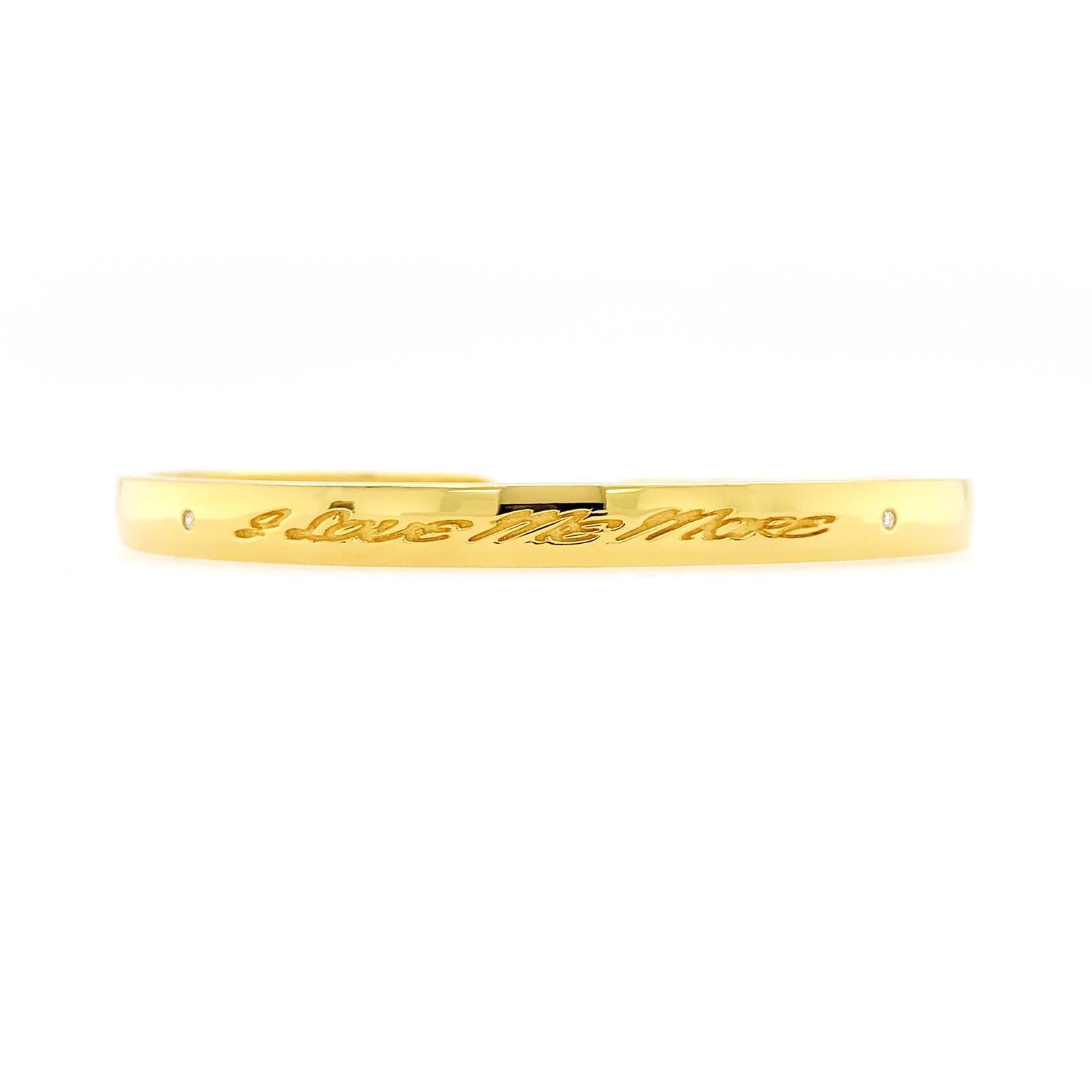 Brilliance underscores this bracelet’s romance. The body is a 5mm wide 18k yellow gold bangle with a flat surface and strong polish. It bears the engraved phrase 'I love me more.' Round brilliant cut diamonds rest on either side of the message,