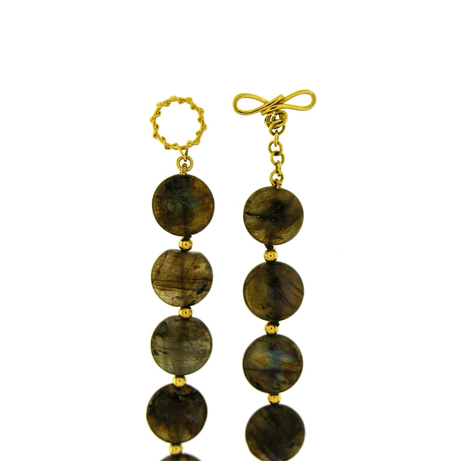 Opalescent luster prized in labradorite is the focus of this necklace. Carved into disks, the gem is strung on a wire. Each disk differs, some are more transparent and others have more flecks of a blue undertone. A small globe of 18k yellow gold is