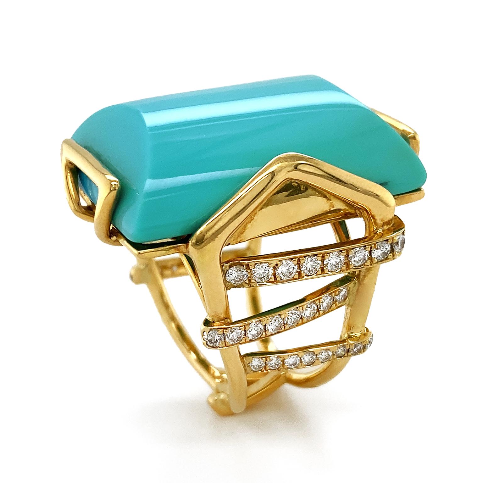 The blue green opacity of turquoise is the culmination of this ring. Its special cut is an elongated cylinder with a curved top and bottom. 18k yellow gold triangular shaped prongs secure the gem and lead to a multi split band. More gold strands