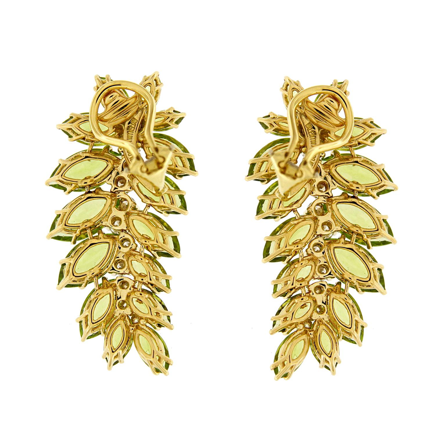 A delicate silhouette of a leaf is illustrated by lustrous peridots and brilliant cut diamonds for these drop earrings. The earrings feature various marquise cut peridots in verdant hues fanned outward. To emulate the pattern on the leaf, graduated