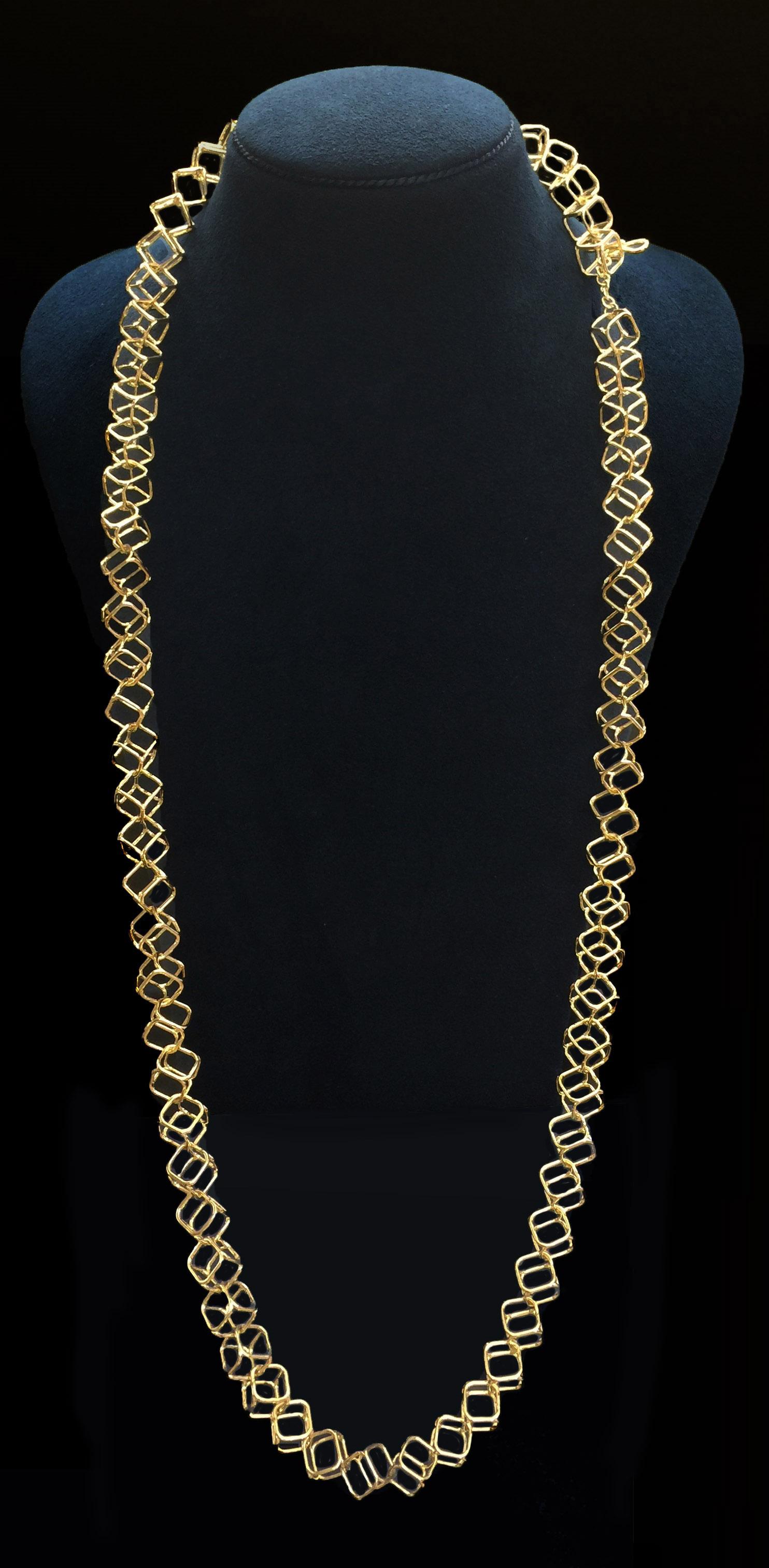 An openwork pattern gives a modern rendition to this chain necklace. Slender bars raise two square outlines to form an openwork cube. This connects to another cube by its corner, forming a chain design made entirely of 18k yellow gold. A knot and