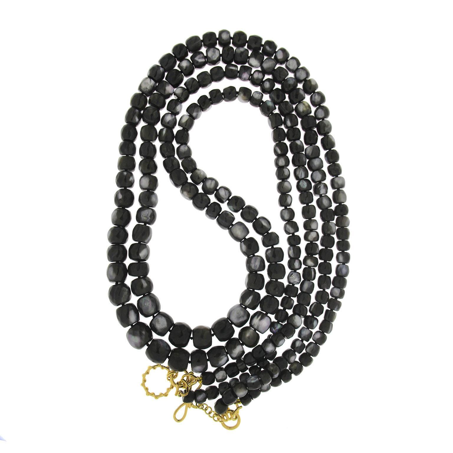 Valentin Magro Multi-Strand Barrel Shaped Faceted Black Mother of Pearl Necklace has a mottled appearance. The main hue on the mother of pearl is black, though grey appears here and there, adding variety. The jewels are carved into barrel shaped