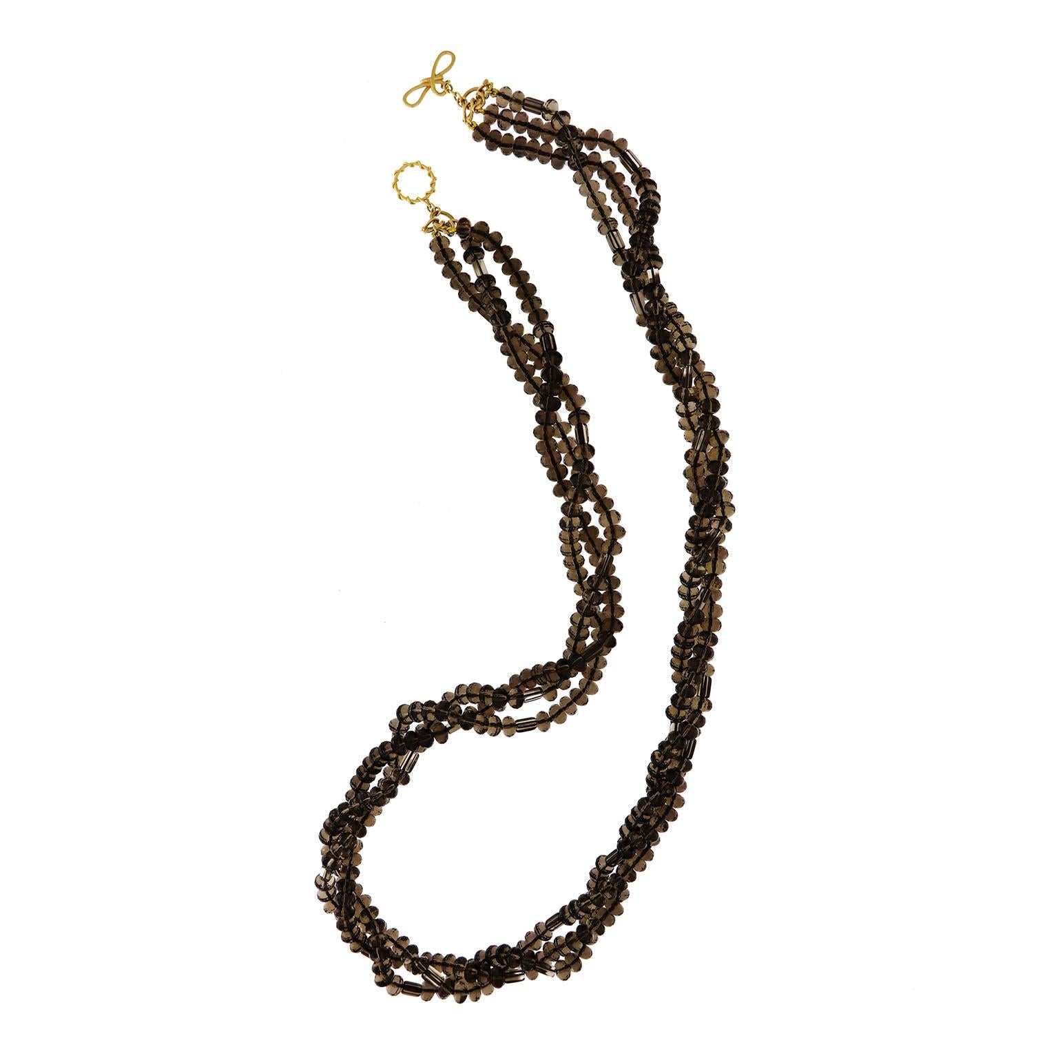 Strand upon strand creates a rope of brown. Transparent smokey quartz is carved into oval beads and strung widthwise onto three cords. They are twisted into a torsade, creating a ropy look. An 18k yellow gold knot and toggle clasp completes the