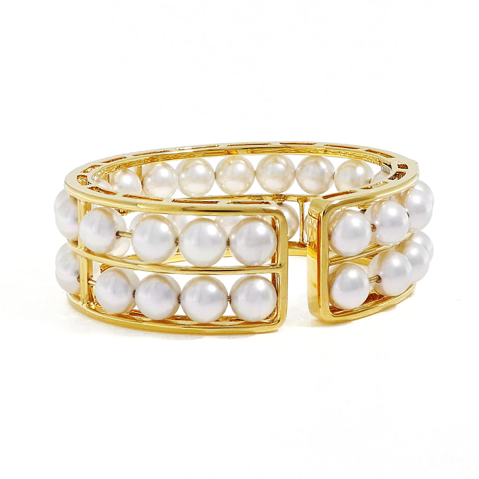 This narrow 18k yellow gold cuff bracelet gives the illusion of floating pearls. As the 38 round Akoya pearls that adorn the cuff, shift and slide, the impression is created. The pearls are secured with gold wire and the 2 gold rows gleam in between